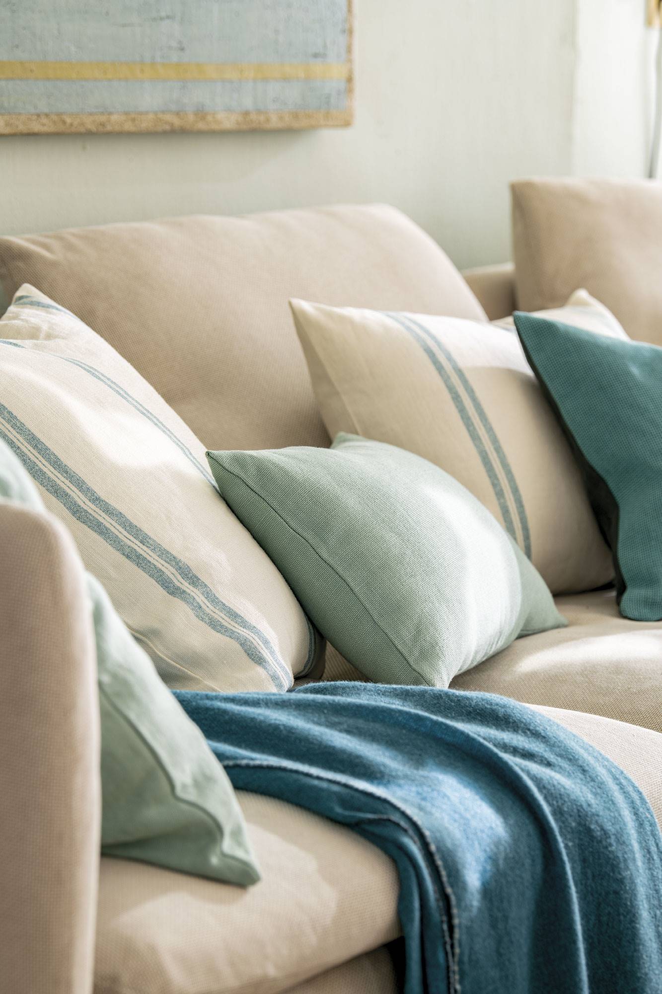 Cojines en tonos mint y turquesa sobre el sofá.