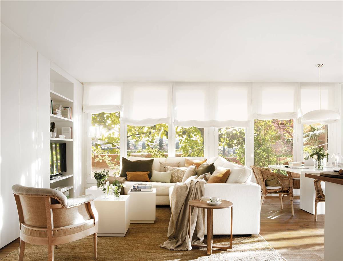 Salón con sofá en L de color blanco y muebles de madera. 