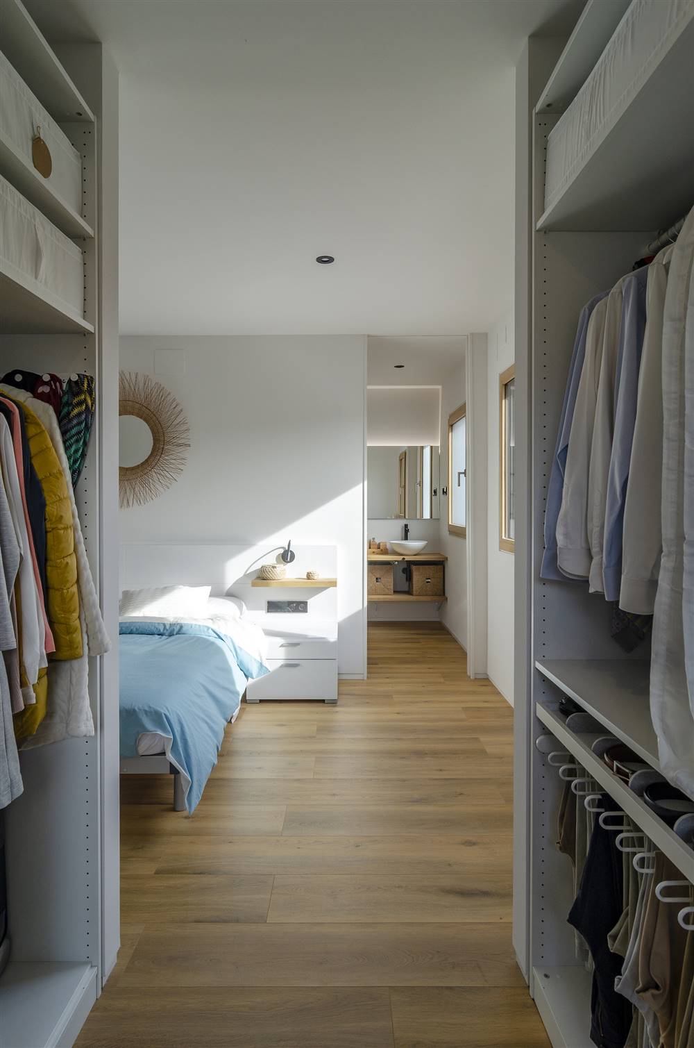 Dormitorio con vestidor blanco y azul con baño en suite en casa pasiva de Arquima