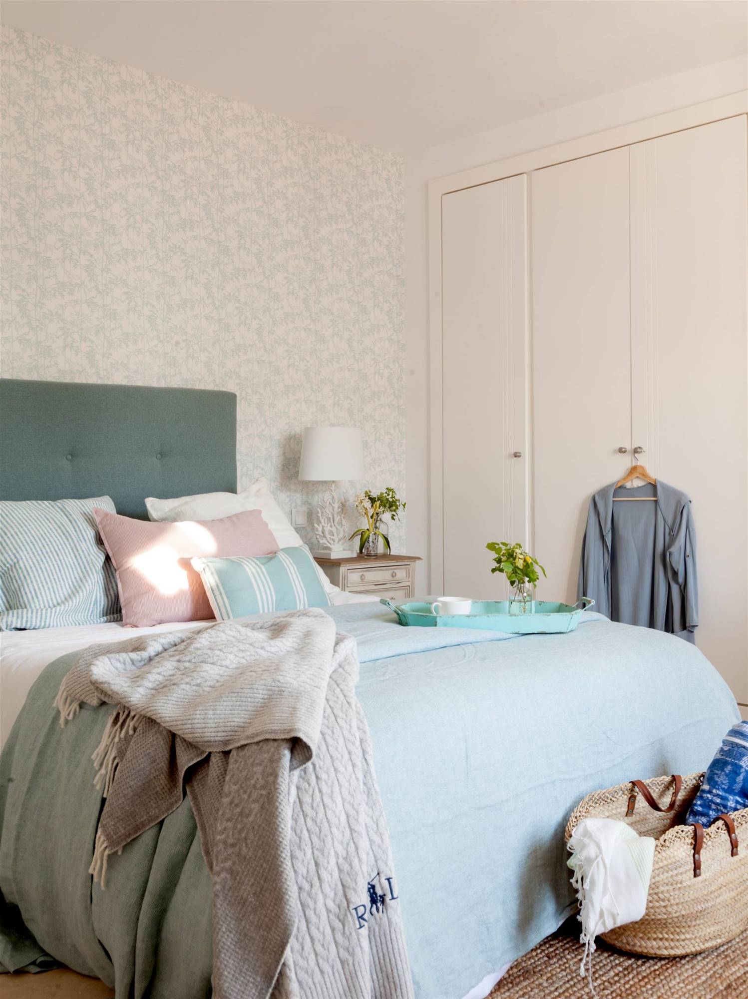 Dormitorio con cabecero en capitoné, papel pintado y armario empotrado.