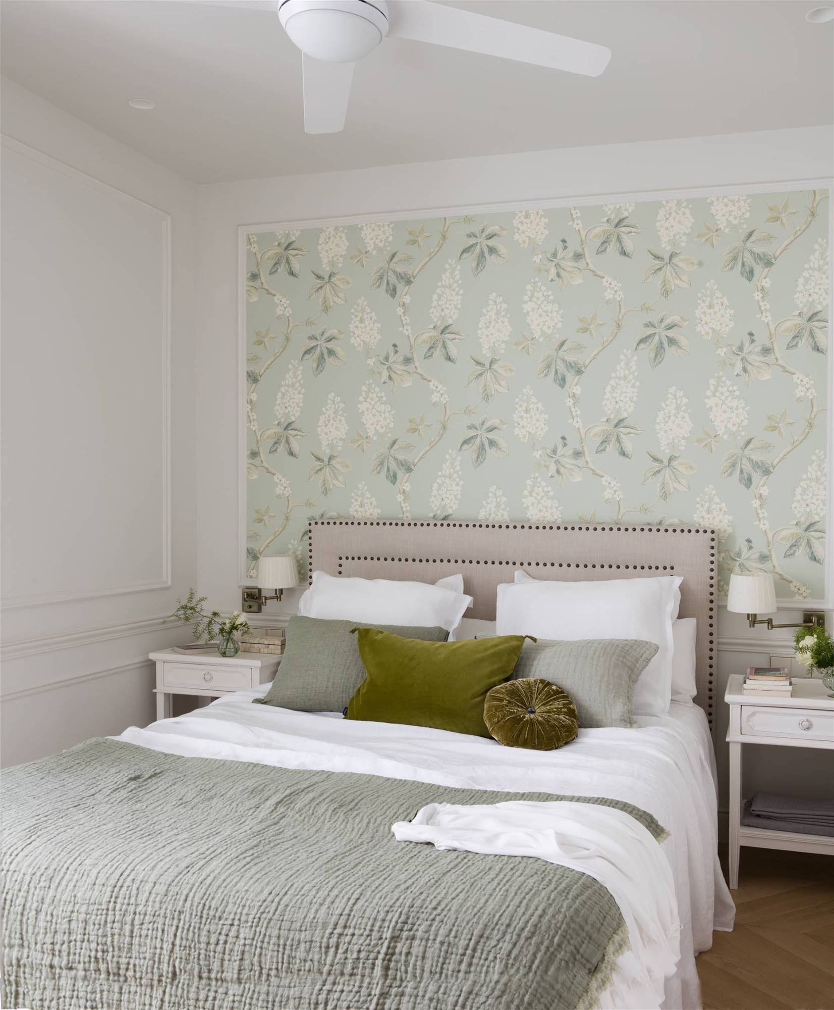 Dormitorio con cabecero de tachuelas y papel pintado de flores. 