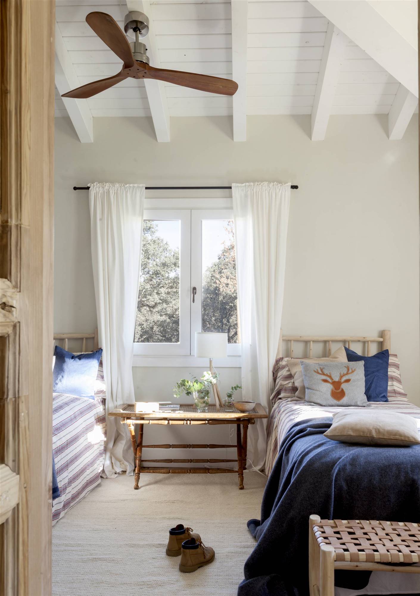 Habitación infatil pequeña con dos camas adosadas a las paredes con una ventana en medio