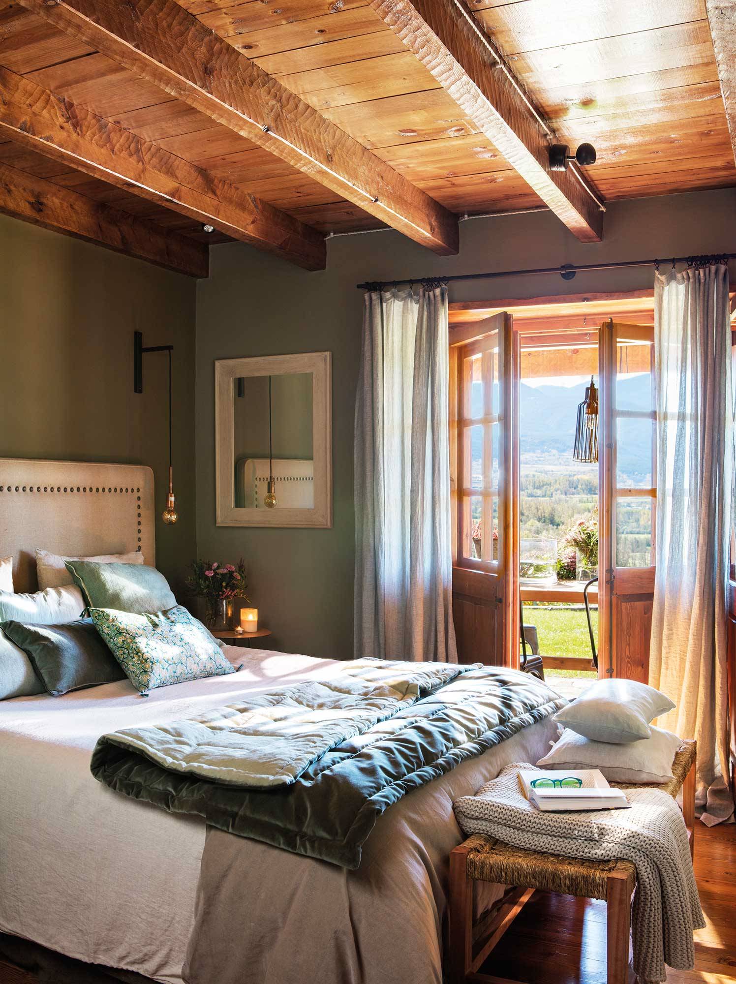 Dormitorio rústico con cabecero tapizado y paredes verdes. 