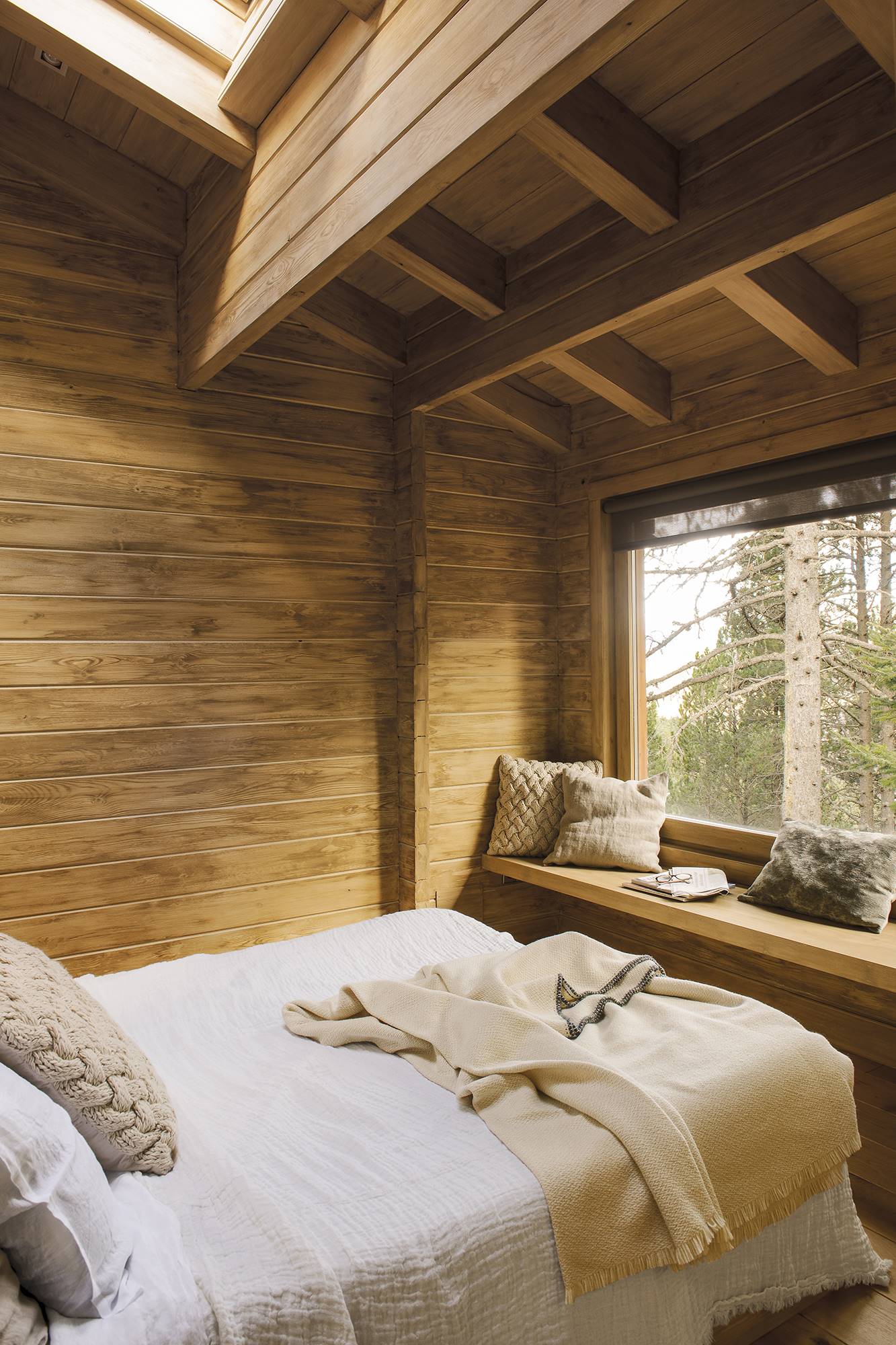 Dormitorio rústico revestido en madera y con ventanal grande. 