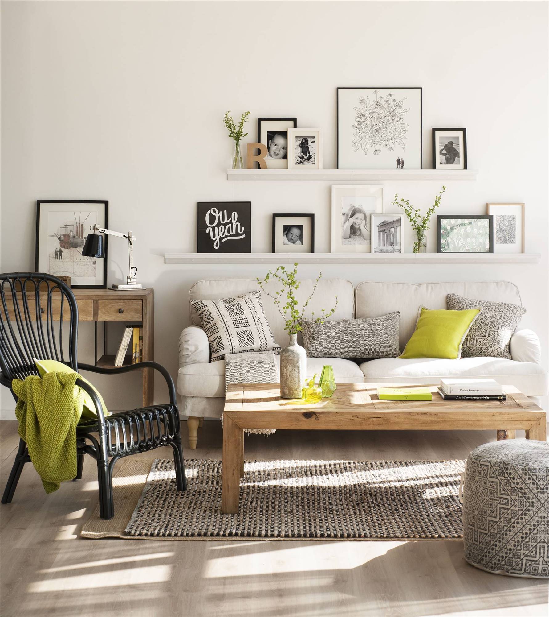 Salón con baldas sobre el sofá con cuadros apoyados y alfombra, puf y cojines con motivos geométricos en blanco y negro.