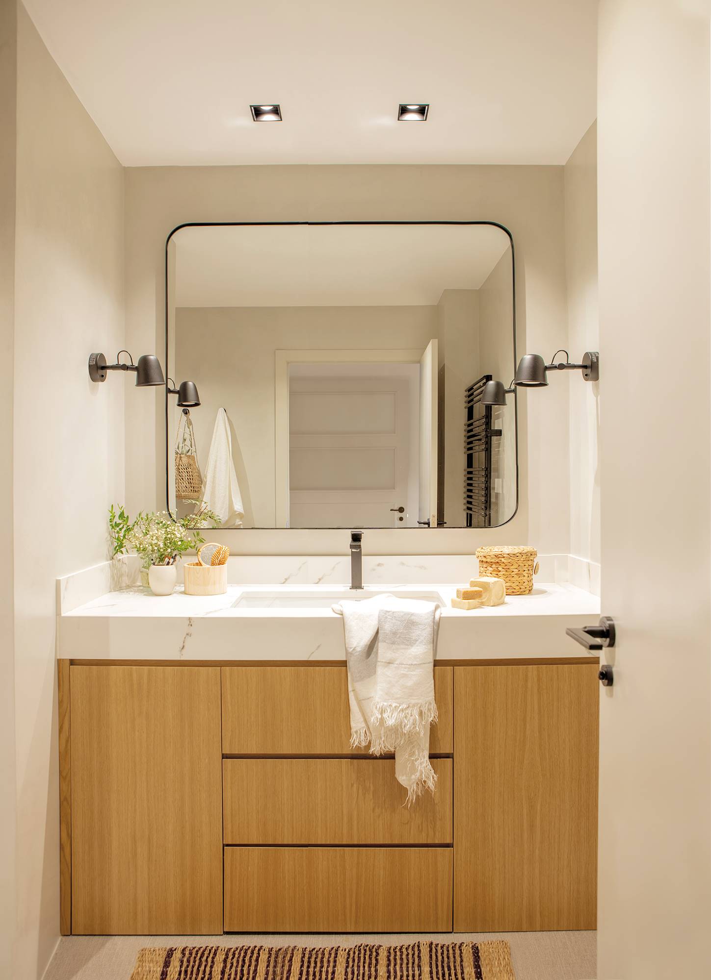 Baño con mueble de baño a medida con cajones y puertas y espejo cuadrado con marco negro. 