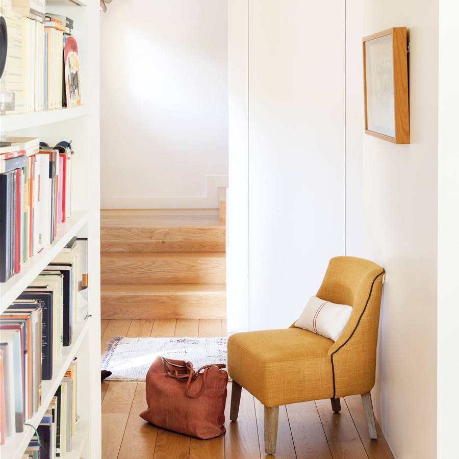 Un rincón de lectura en el pasillo con una librería y una butaca