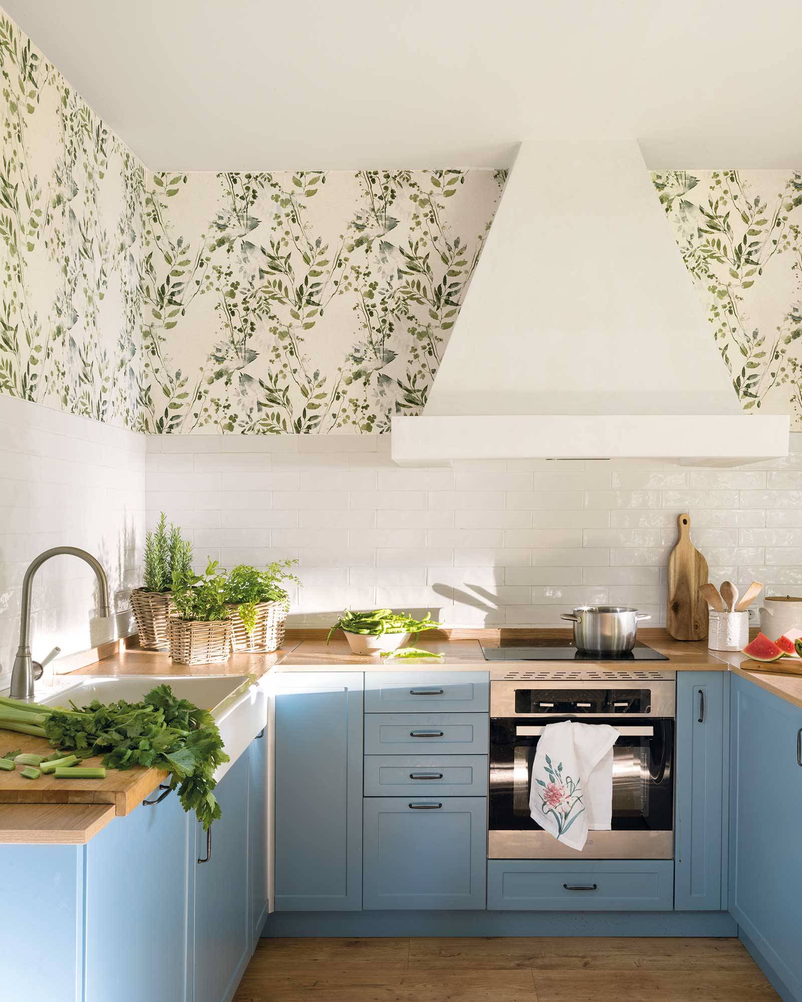 Cocina con campana decorativa, antepecho de azulejos y paredes de papel pintado. 