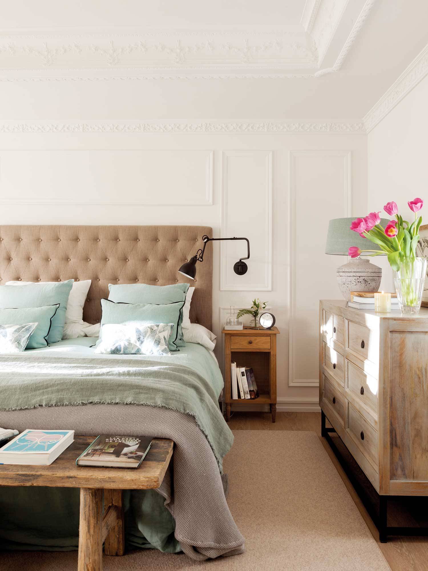 Dormitorio clásico con cabecero en capitoné y muebles de madera lavada. 