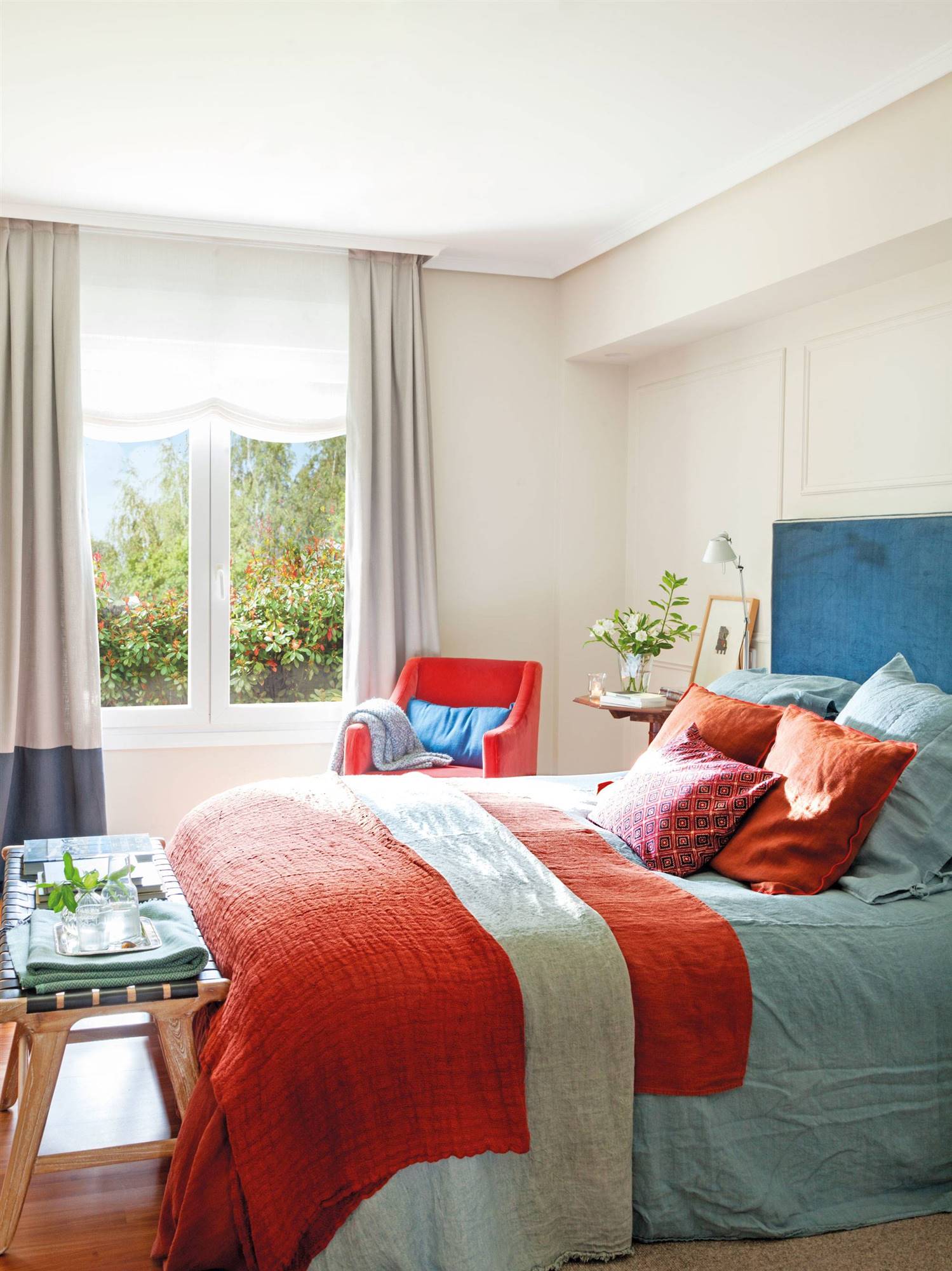 Dormitorio con pared del cabecero con molduras, cabecero azul y detalles en coral