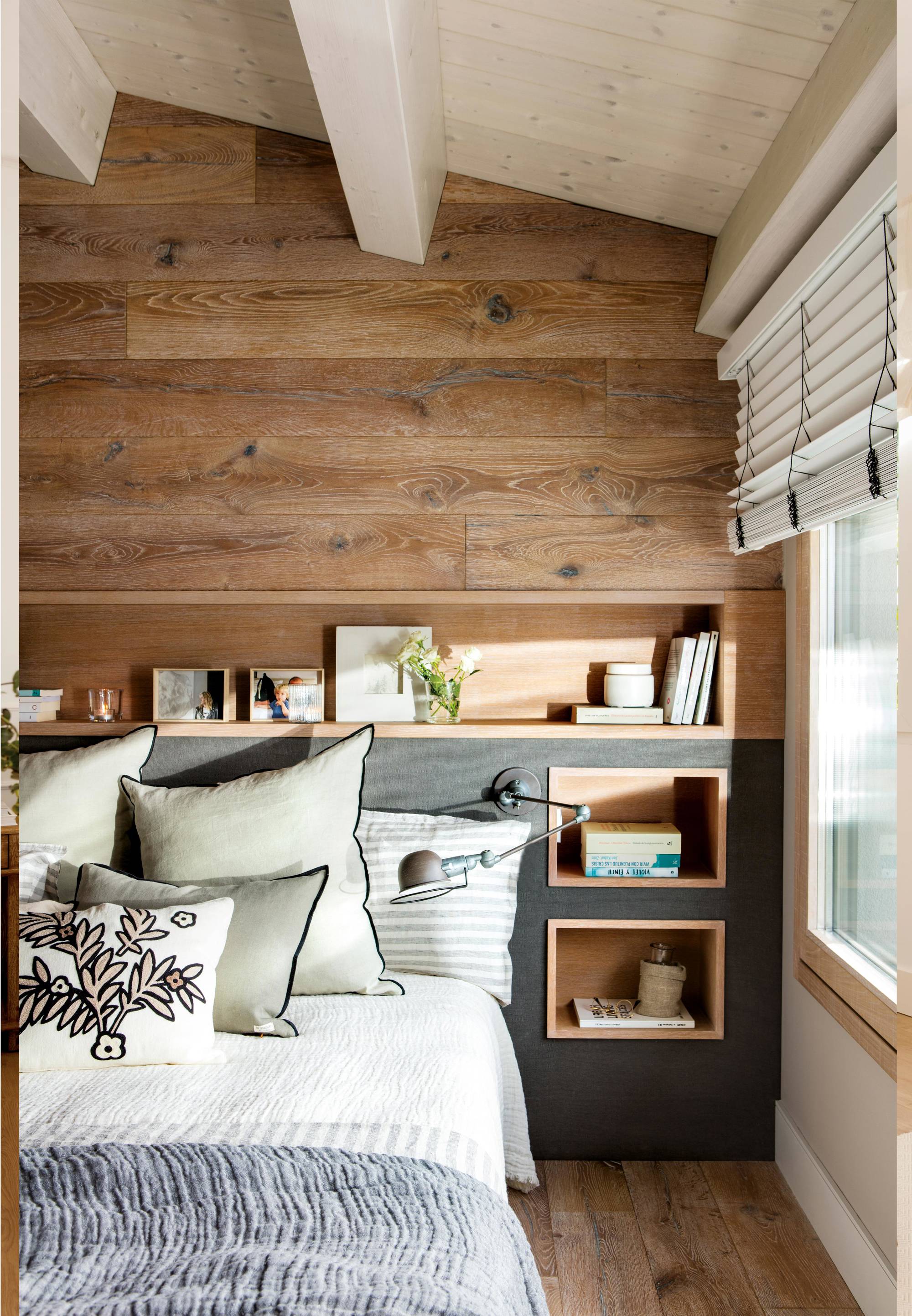 Dormitorio con cabecero de obra y pared revestida de madera.