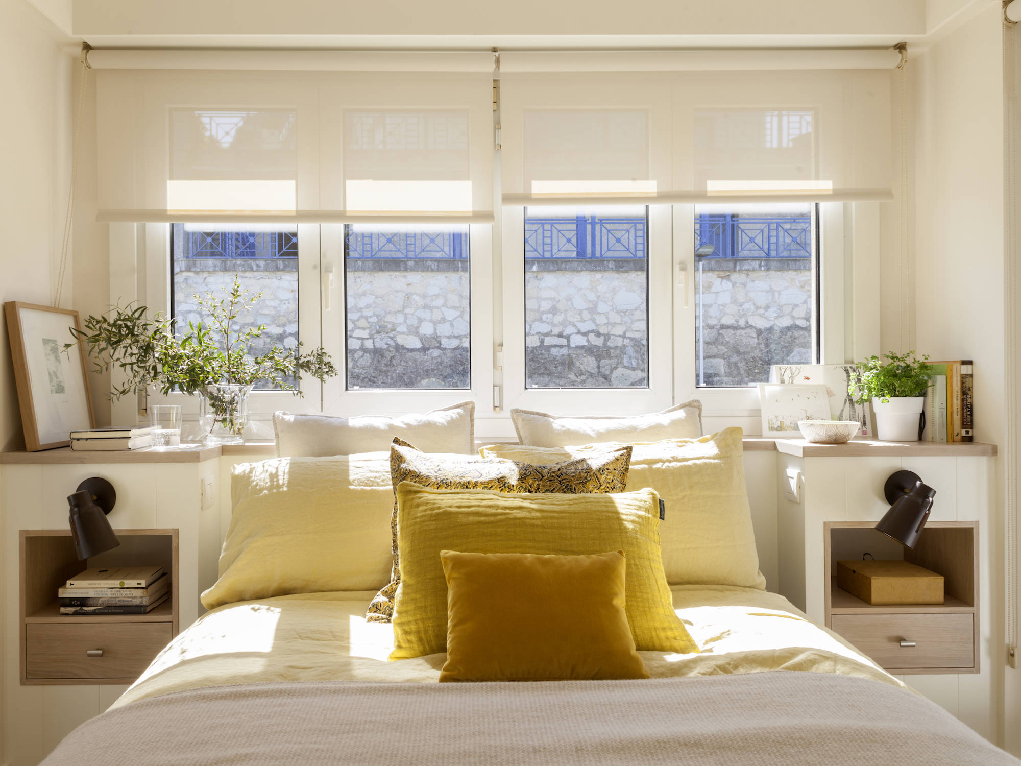 Dormitorio con ventanas blancas y cojines ocres