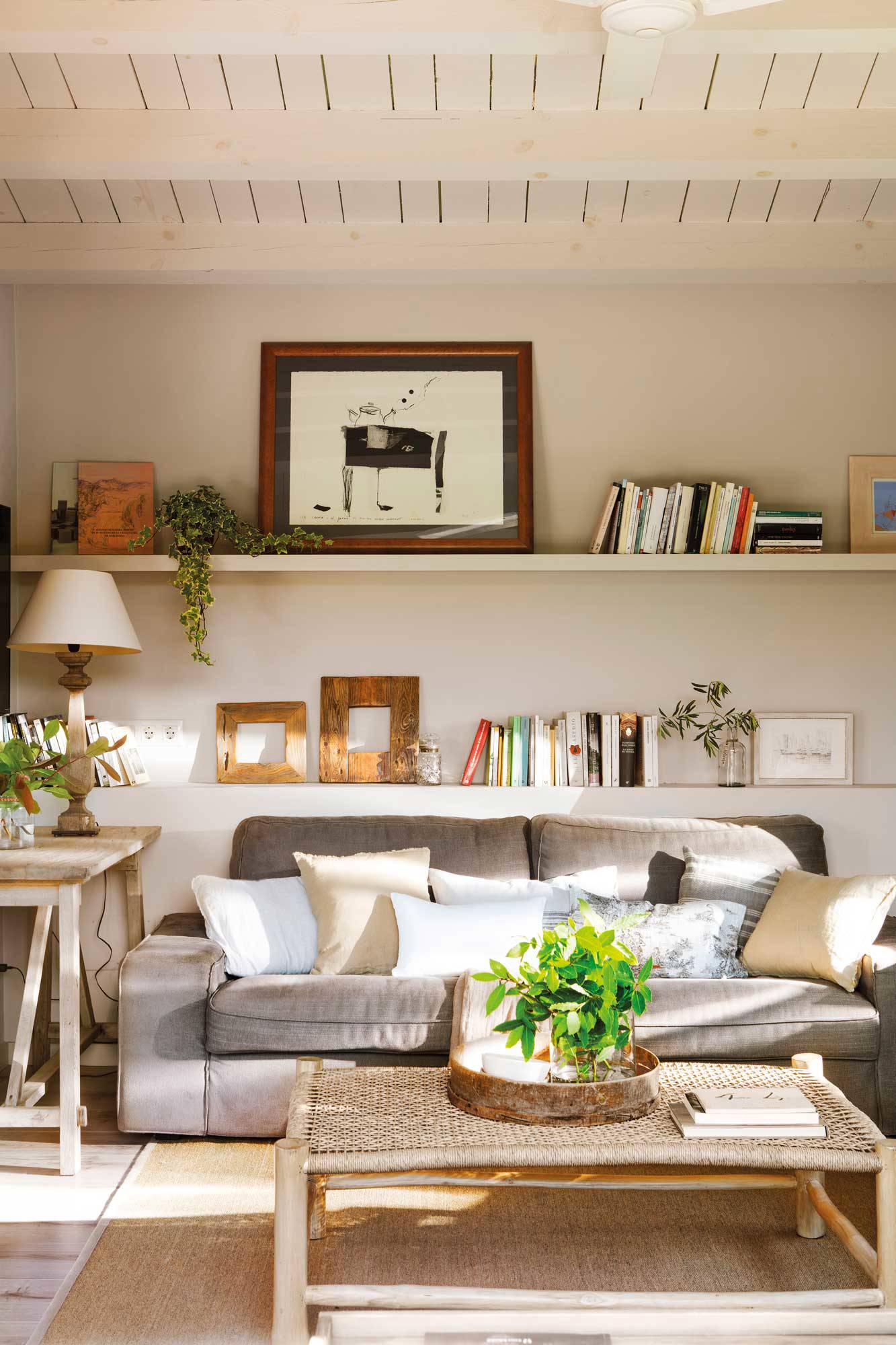 Salón con vigas de madera blancas y sofá gris
