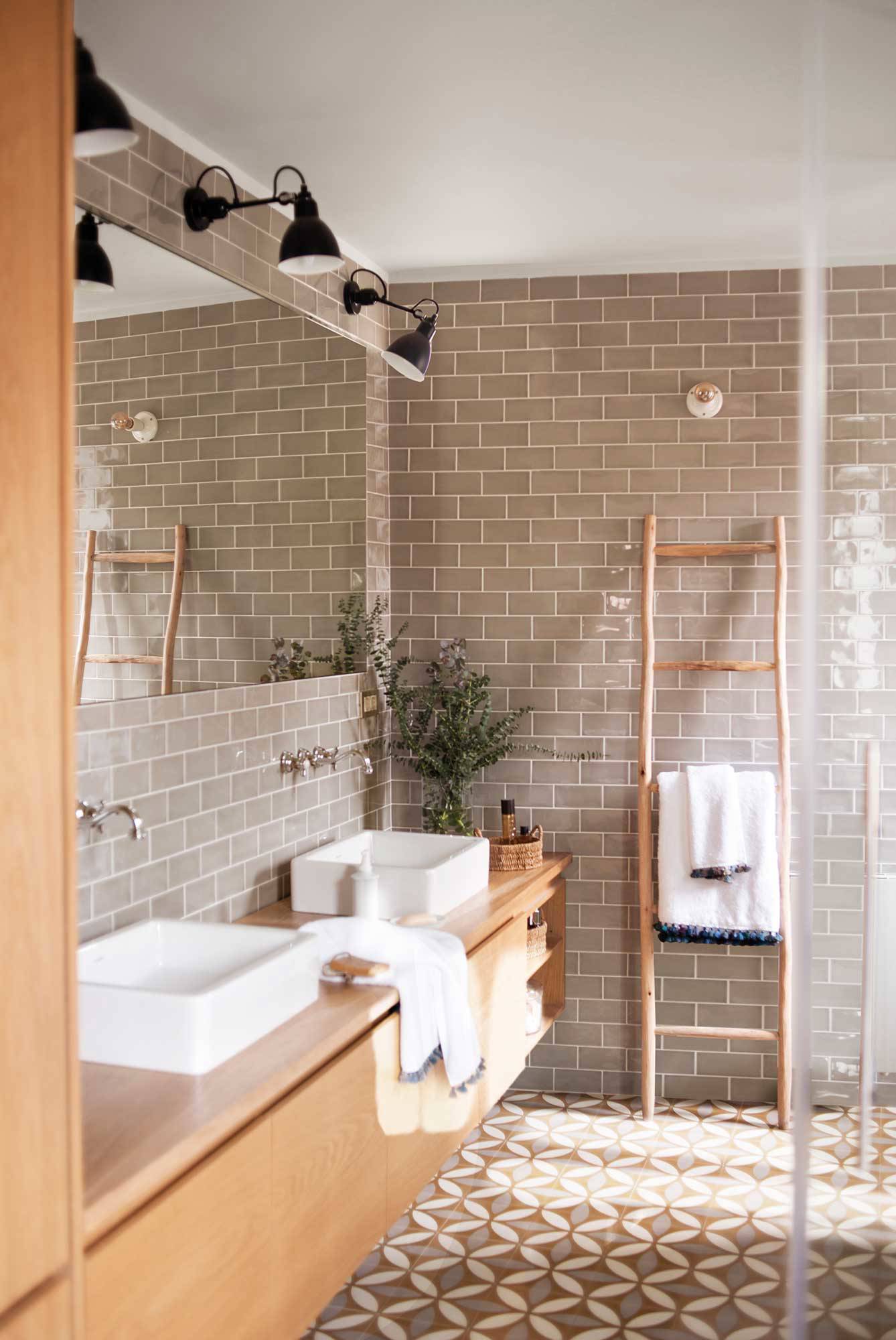 Baño con baldosas y hidráulicos y azulejos tipo metro con acabado brillo. 