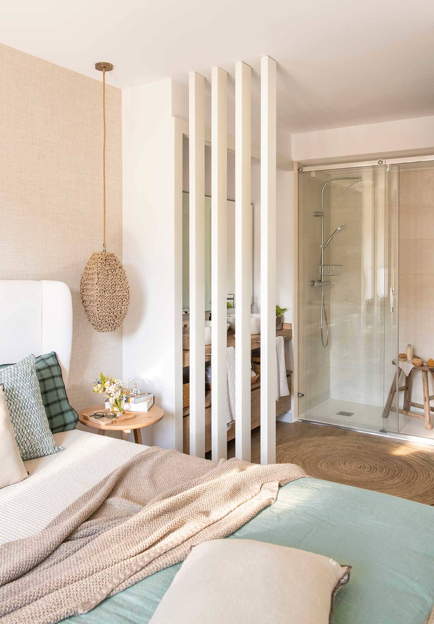 Dormitorio con celosía de madera blanca que separa del baño