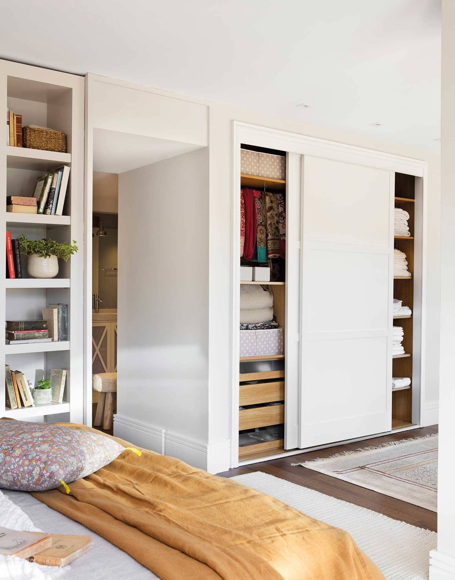 Dormitorio con zona de librería y armarios con puertas empotradas.
