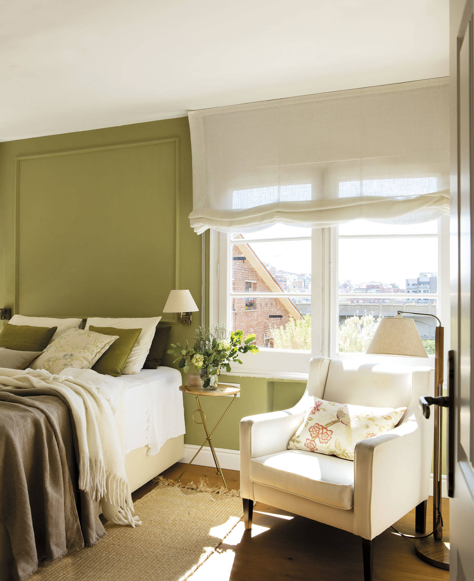 Dormitorio con cabecero verde y ropa de cama a juego. Cerca del armario, una butaca blanca.