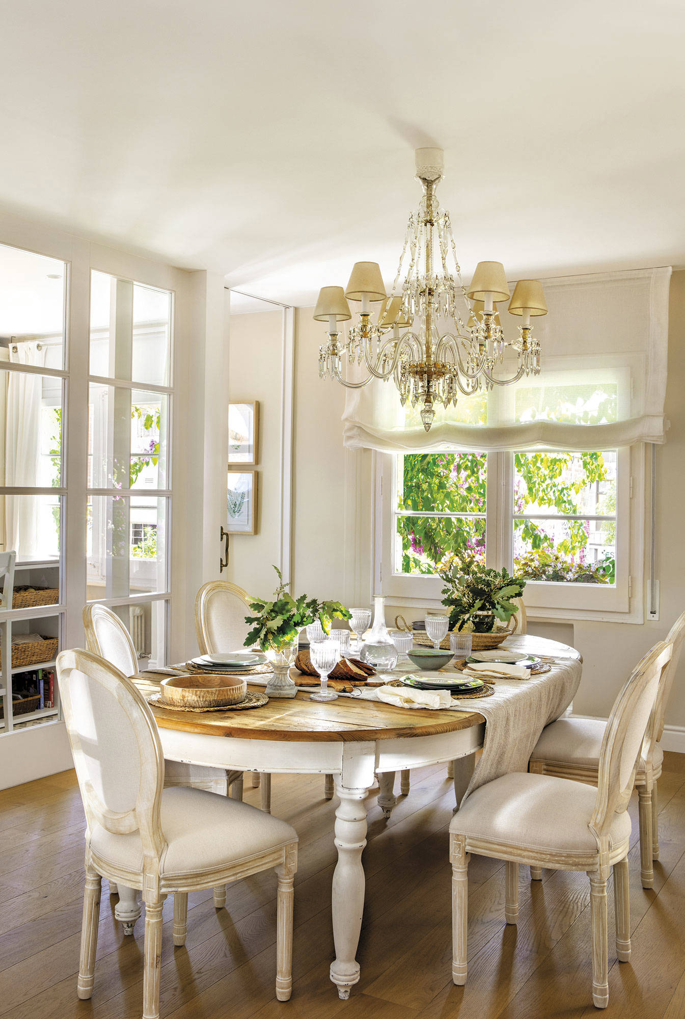 Comedor clásico con mesa de madera, sillas tapizadas y lámpara de techo de araña.