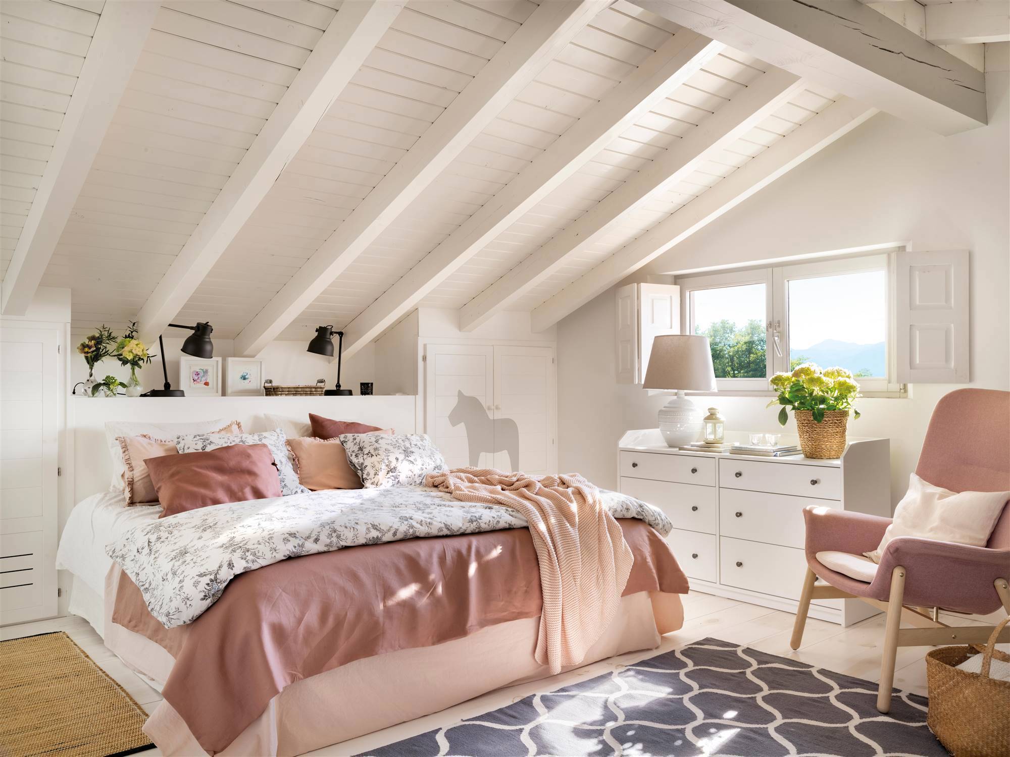 Dormitorio con cómoda blanca y butaca rosa. 