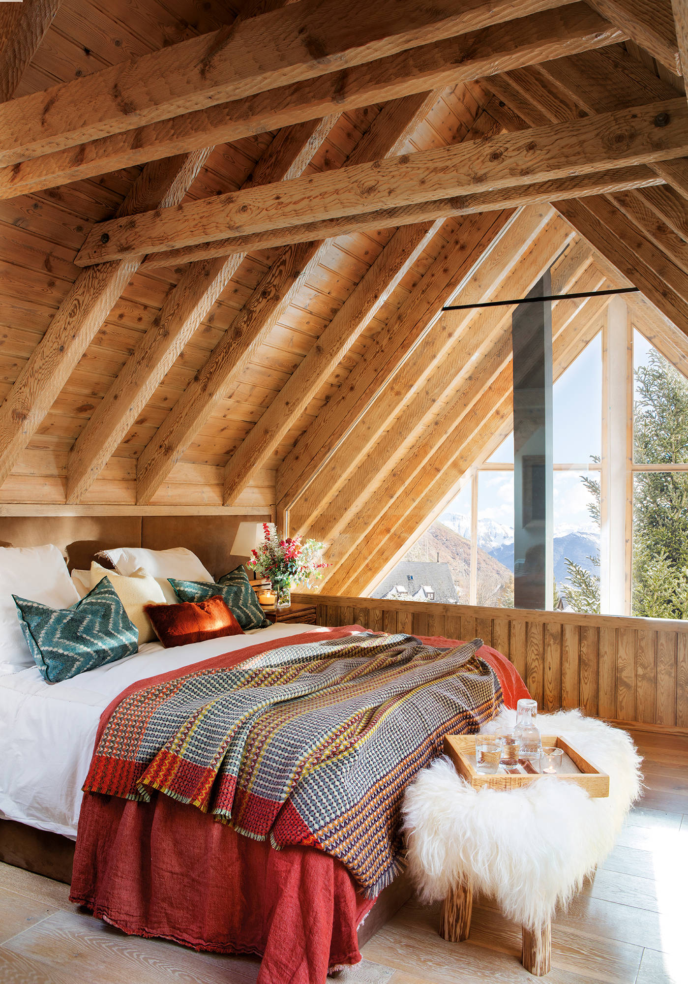 Dormitorio abuhardillado con cama vestida de invierno.