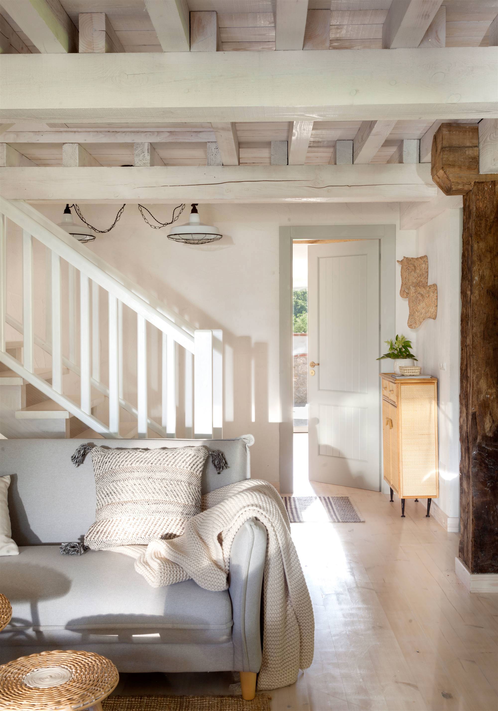 Salón con escalera blanca y consola de madera.
