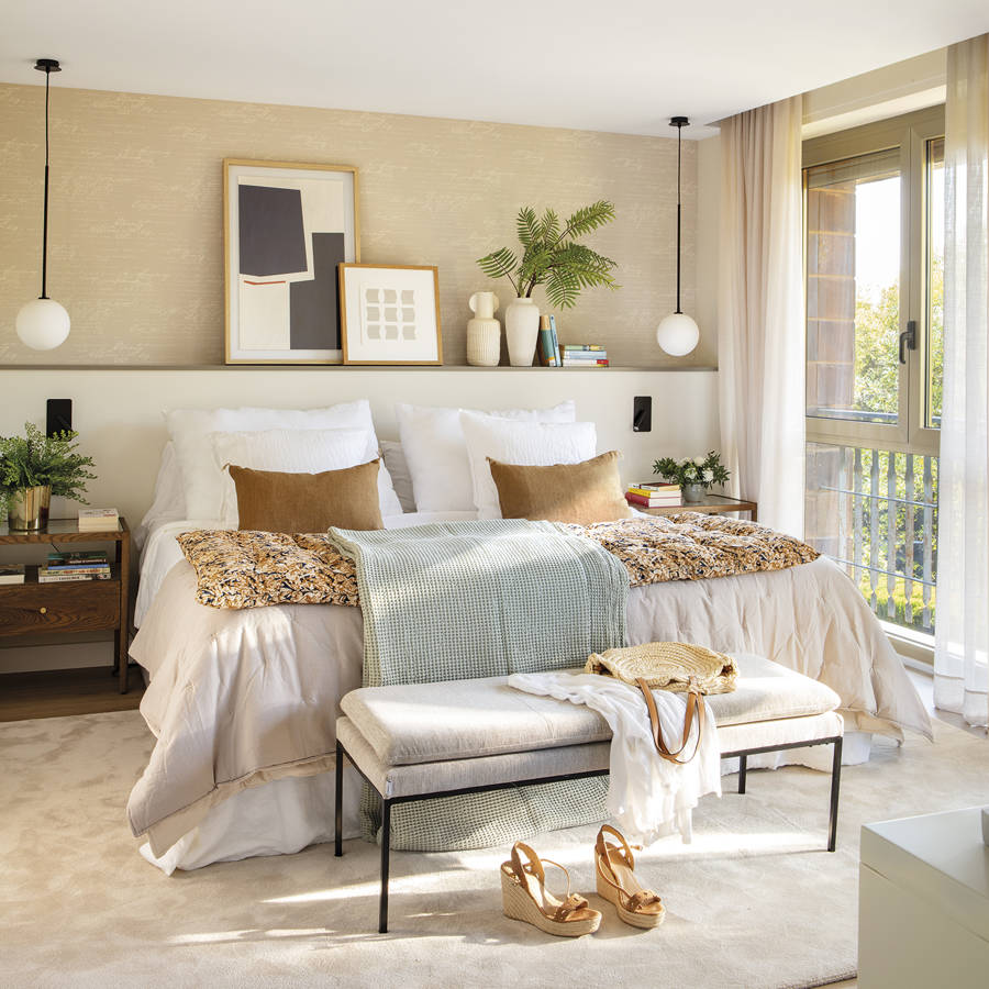 Dormitorio cálido con papel pintado beige y cabecero con repisa