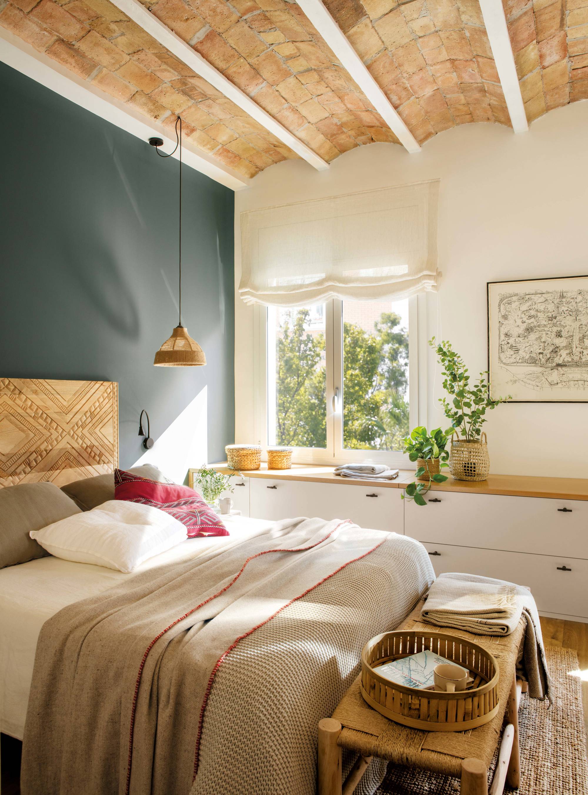 Dormitorio con cabecero de madera y mueble bajo la ventana