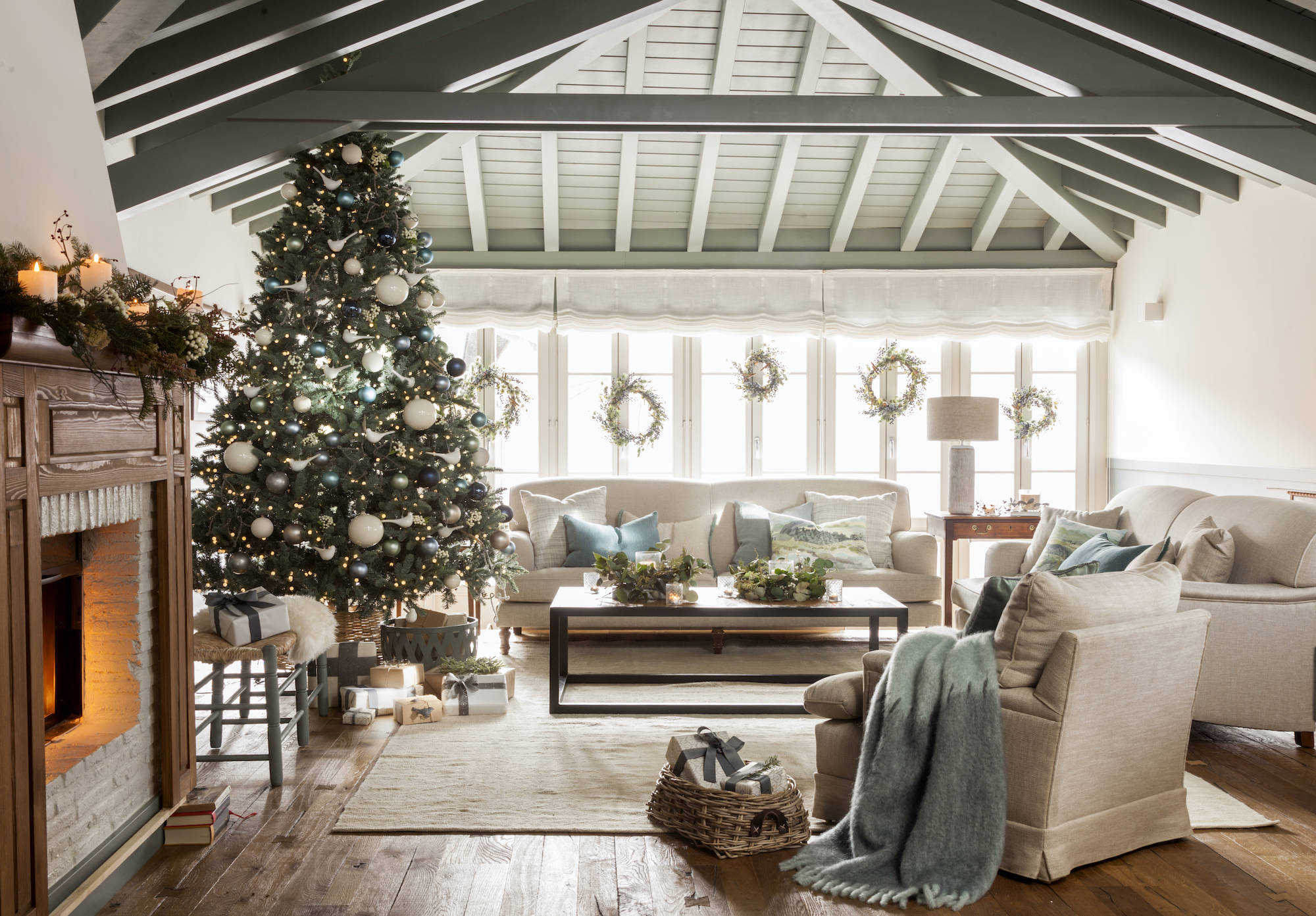 Salón rústico con vigas pintadas y árbol de Navidad.