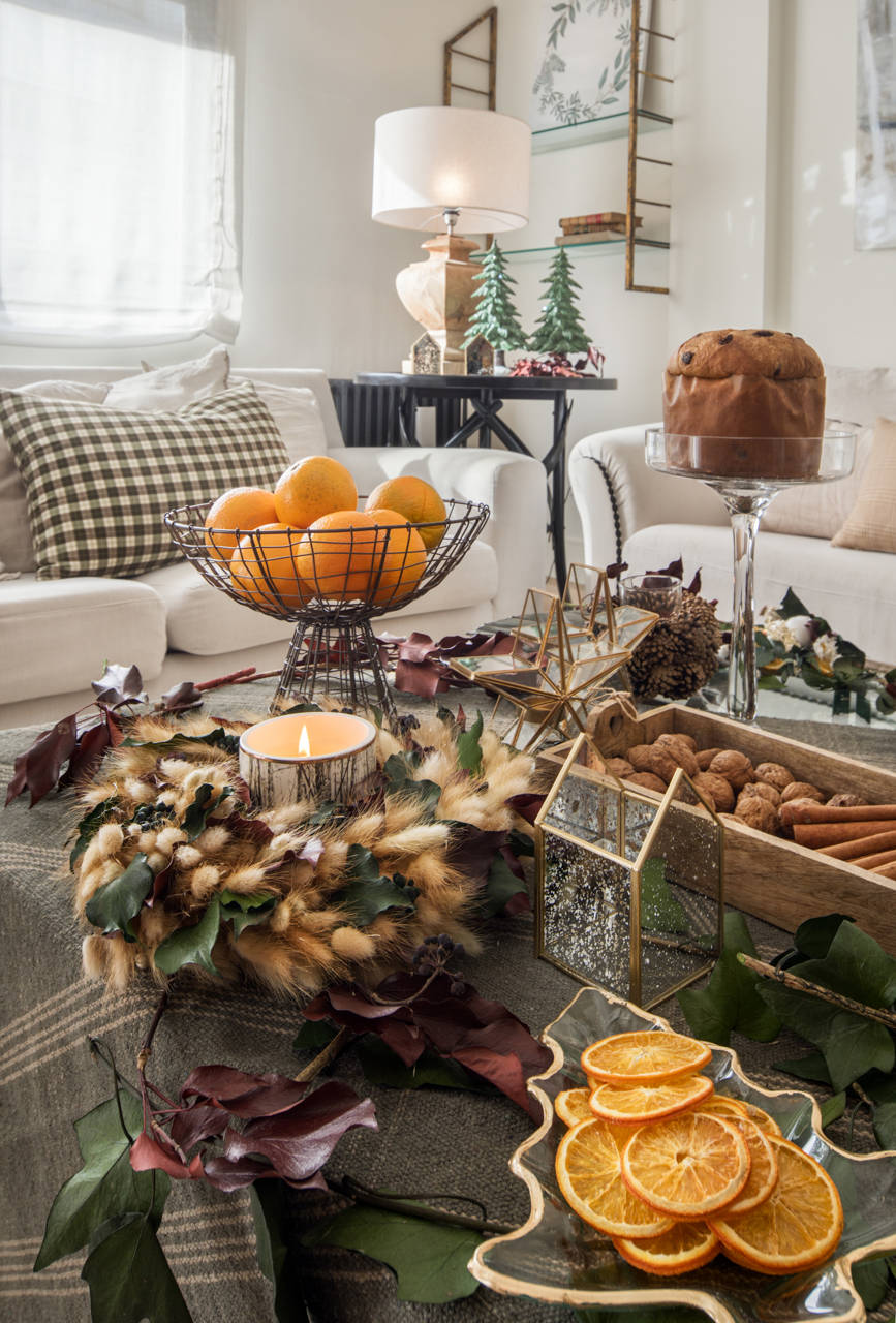 Salón con mesa de centro con mantel verde de cuadros, adornos navideños y dulces festivos.