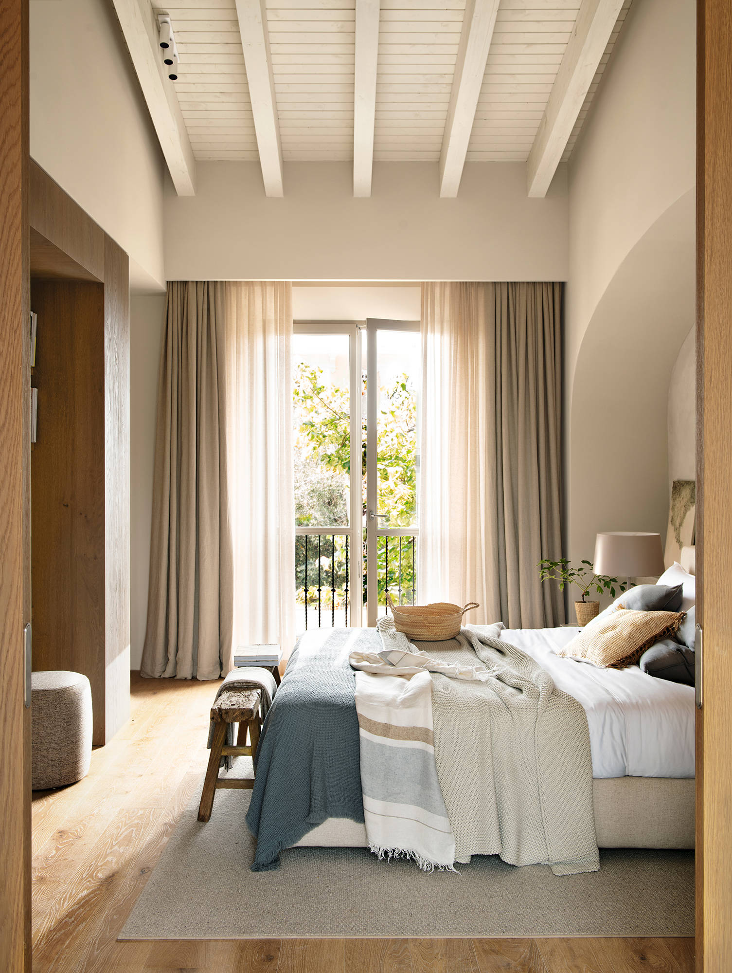 Dormitorio con techo alto inclinado y con vigas blancas