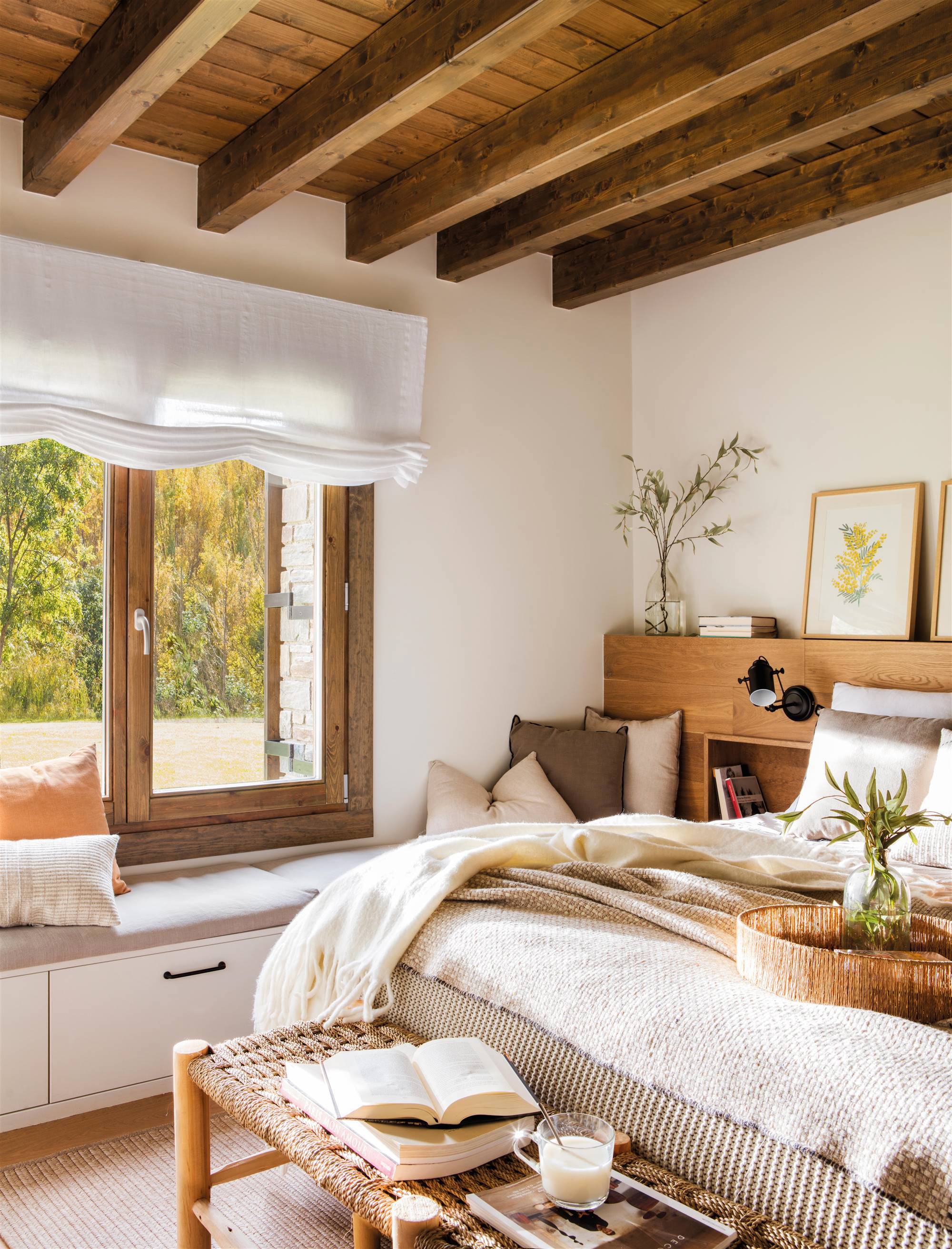 Dormitorio cálido con vigas de madera, cabecero de madera y ropa de cama en tonos neutros.