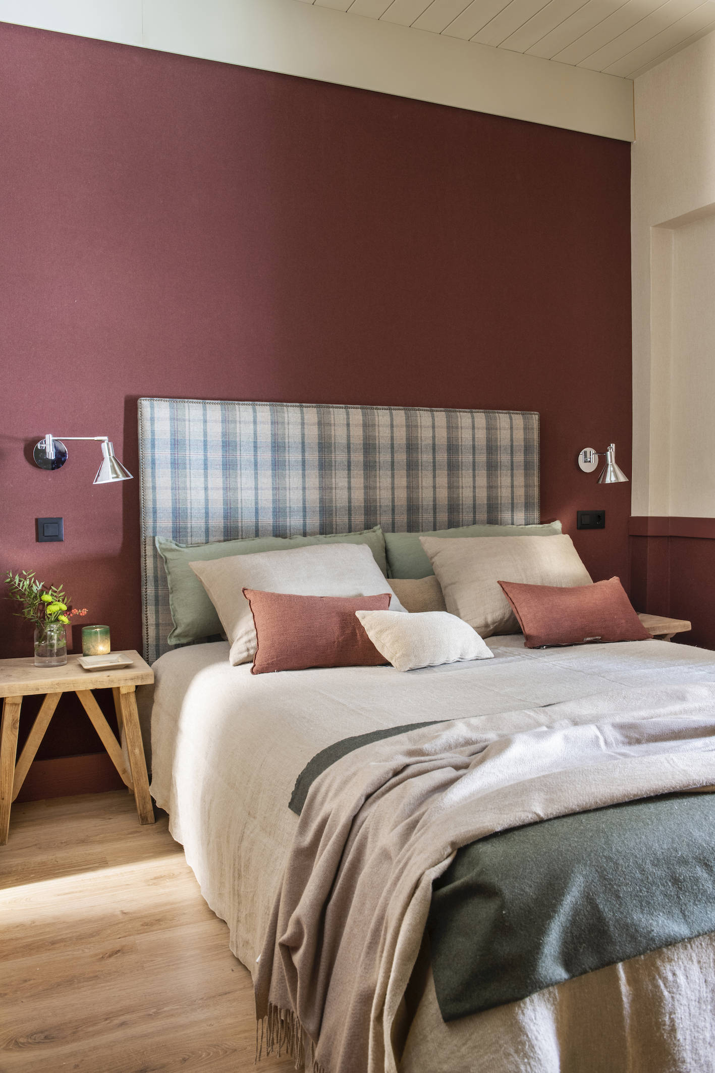 Dormitorio con papel pintado en color granate, cabecero tapizado a cuadros.