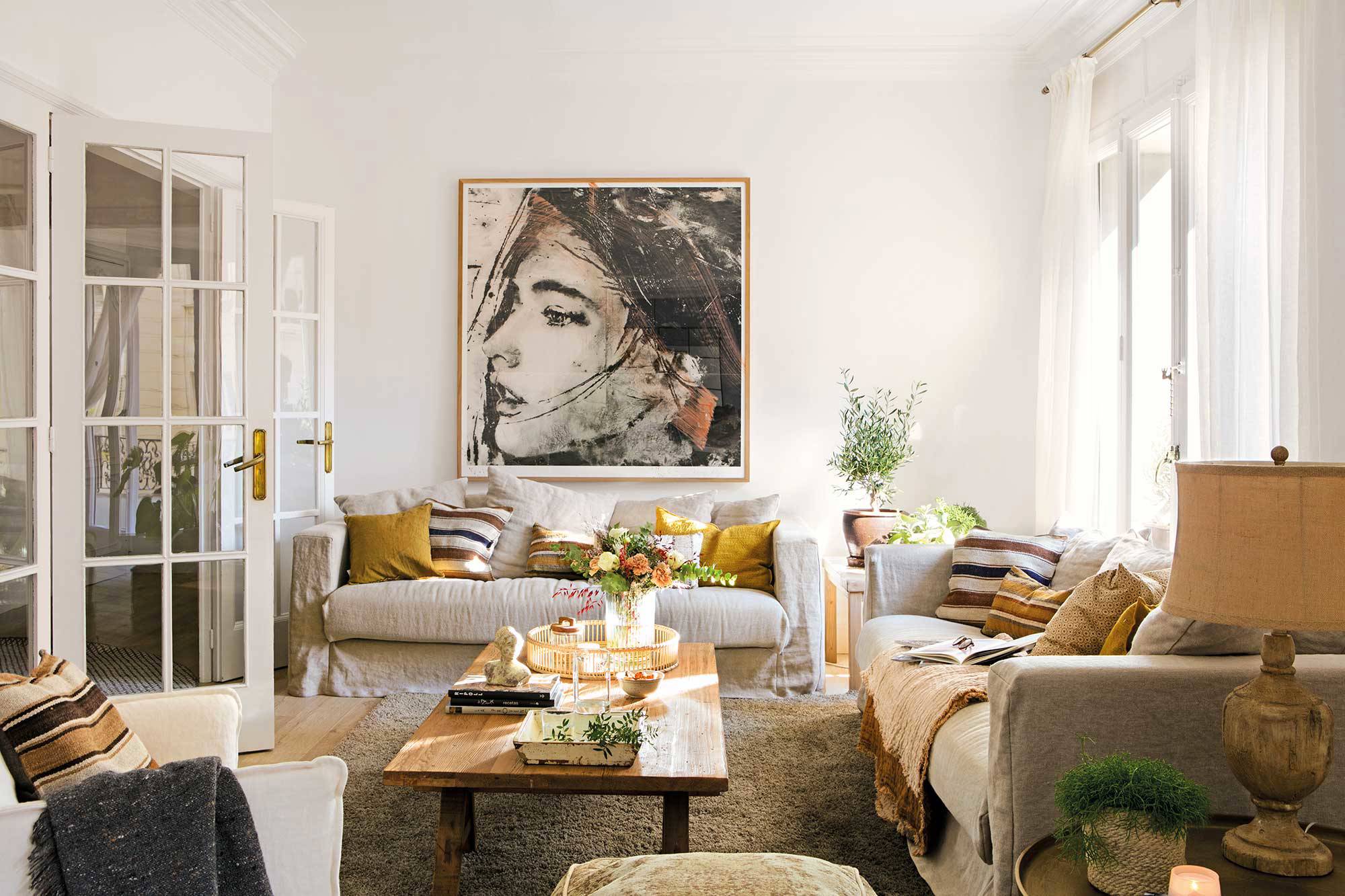 Salón con sofás de color beige y gran cuadro en la pared.