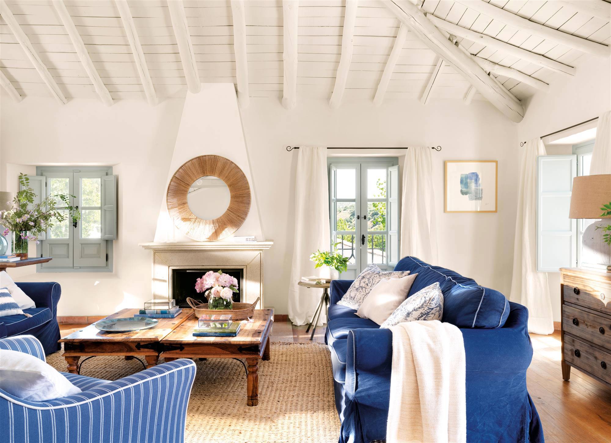 Salón con chimenea, sofás azules y butaca azul con rayas blancas.