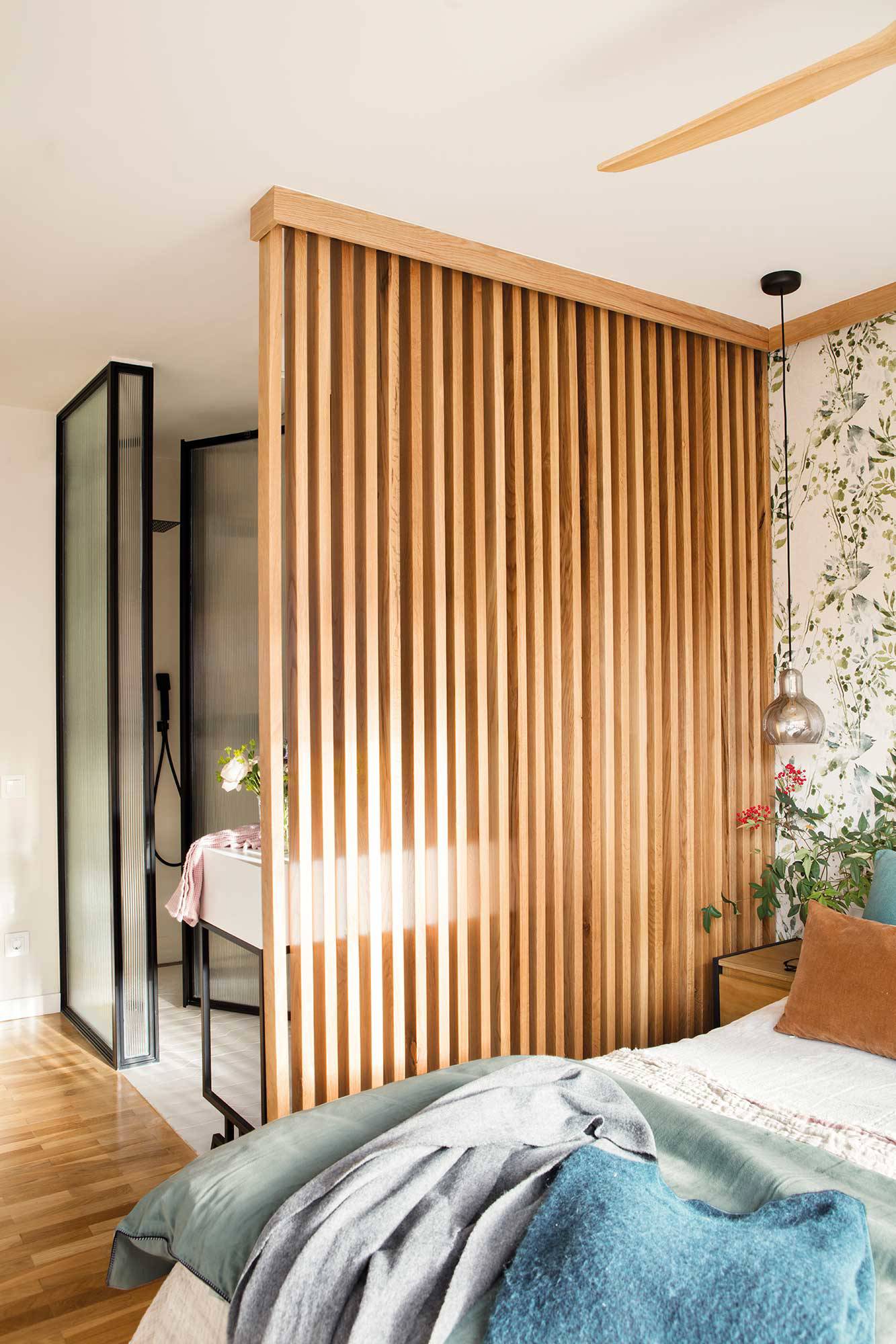 Dormitorio con baño integrado y celosía de madera como elemento separador de ambientes.
