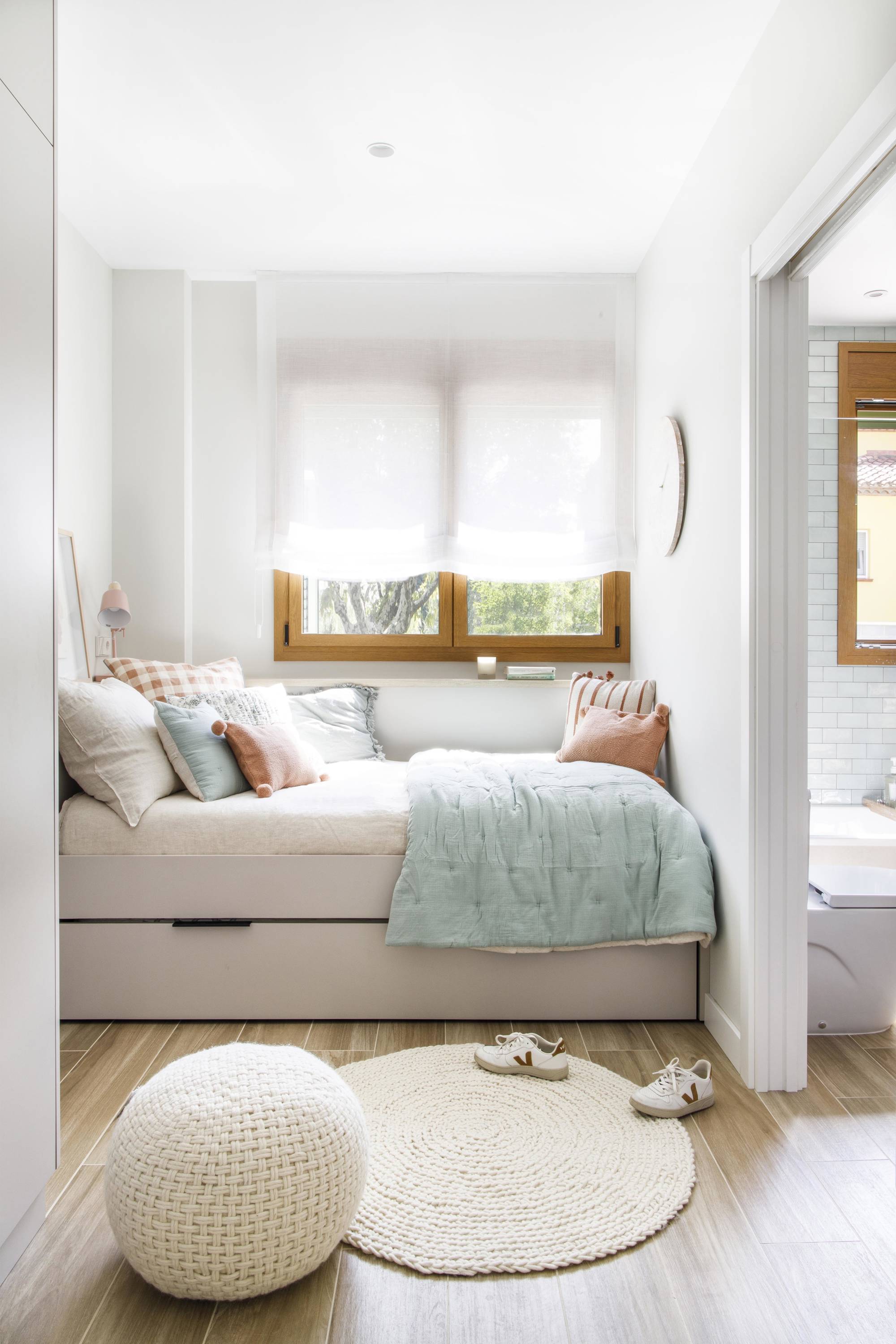 Dormitorio infantil con cama con cajones, armario blanco y puff y alfombra de fibras,