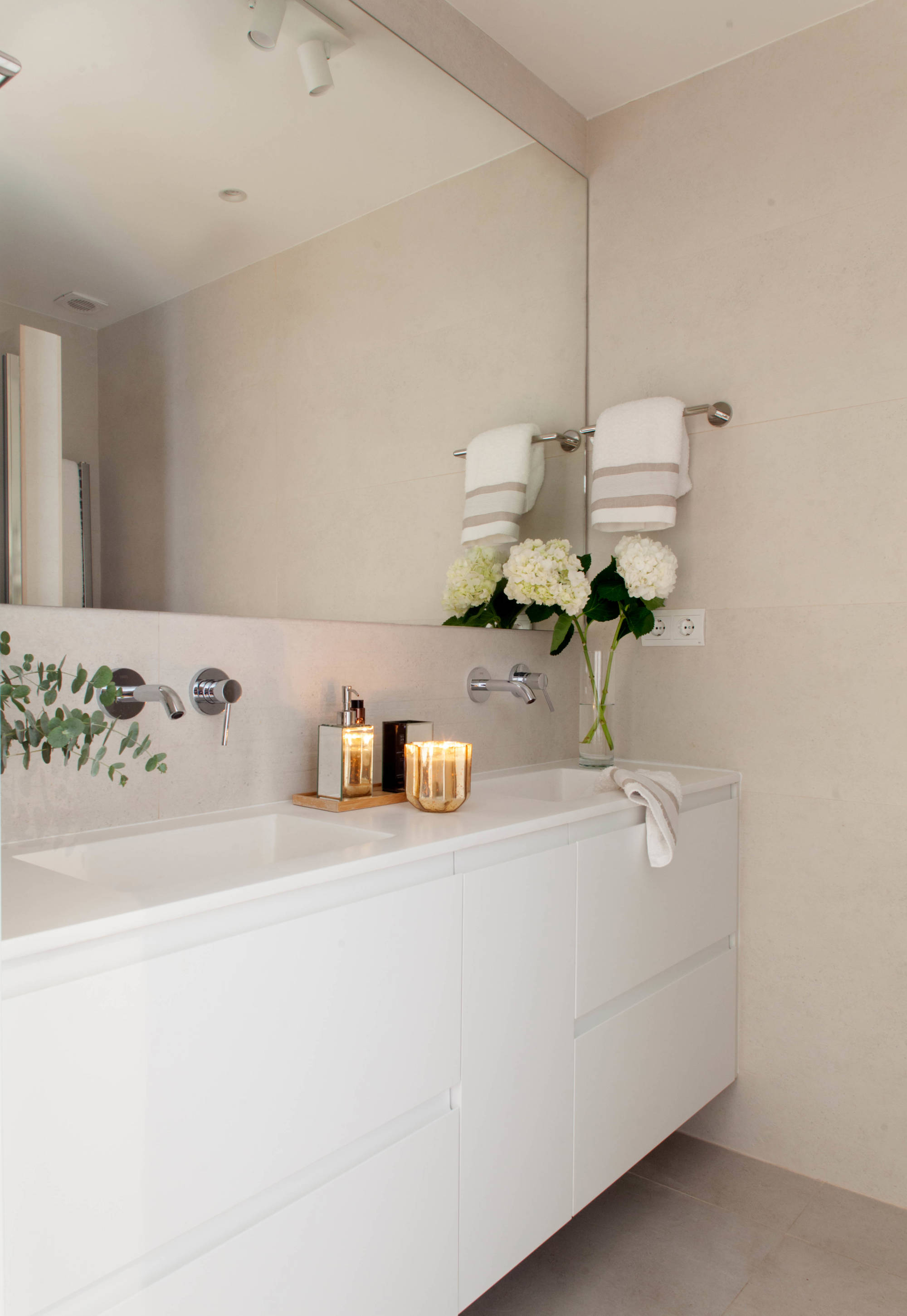 Baño principal con mueble blanco sin tiradores y espejo hecho a medida de pared a pared. 