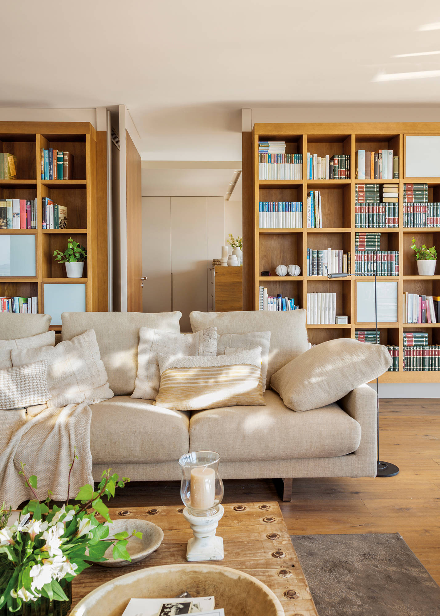 Salón con sofá blanco y librerías de madera simétricas
