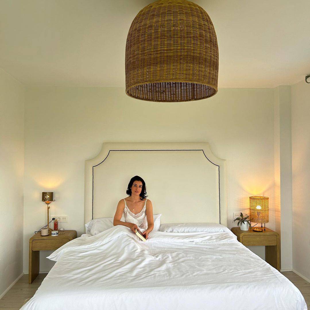 El dormitorio de Blanca Romero con cabecero claveteado y mesillas de madera.