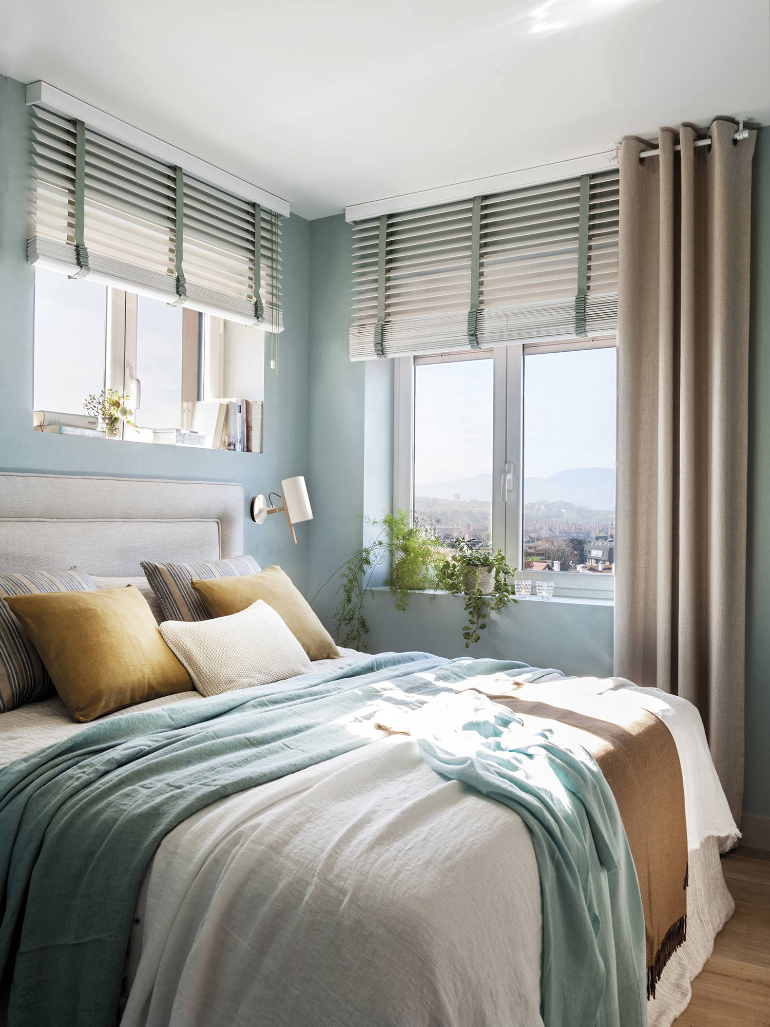Dormitorio pequeño empapelado en color aguamarina, con cortinas y venecianas.