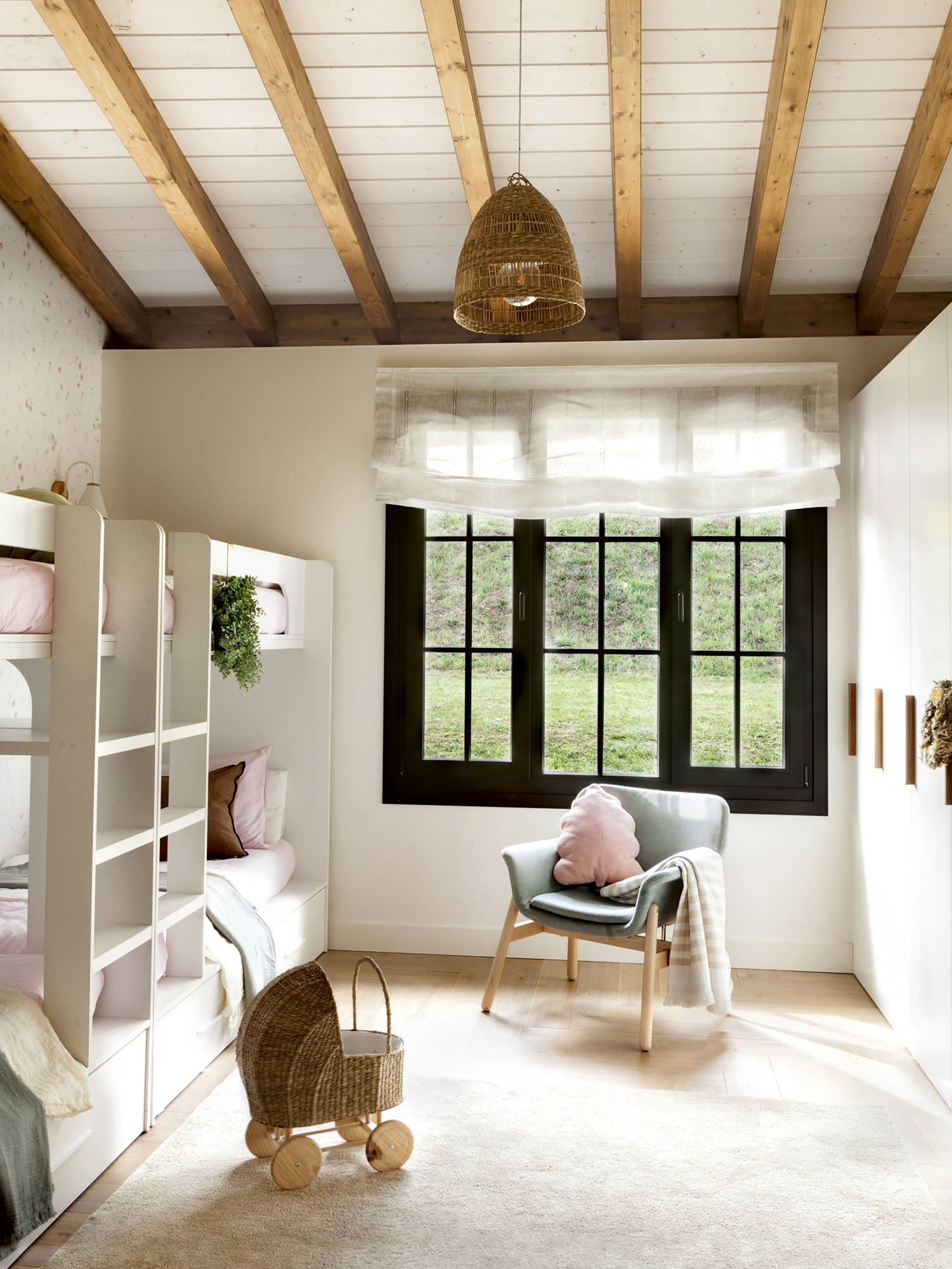 Habitación infantil con literas tipo nido, armario blanco, alfombra y vigas de madera. 
