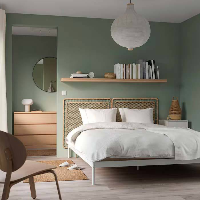 Dormitorio de IKEA pintado en verde con cabecero de ratán y muebles de madera.