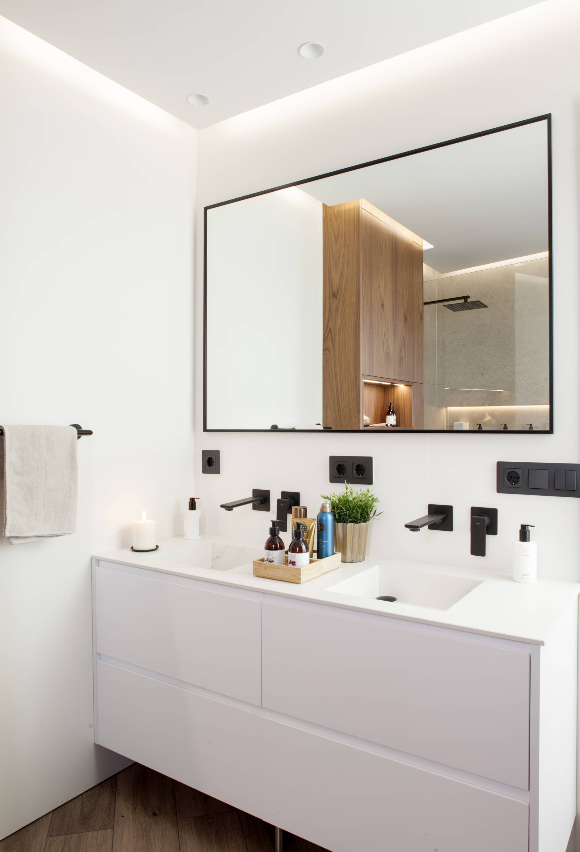 Baño con doble lavabo, grifería y espejo negro y mueble blanco sin tiradores. 