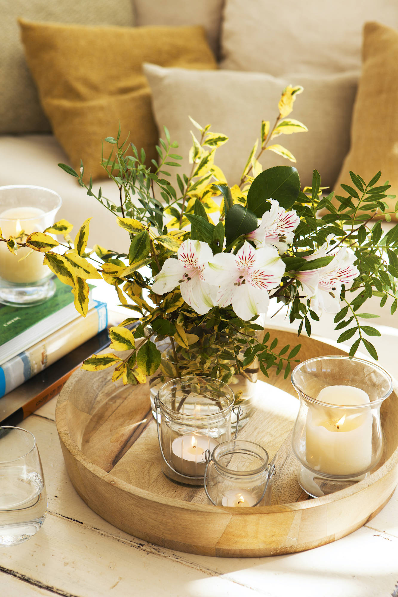 Mesa de centro decorada con bandeja redonda y jarrón con flores.