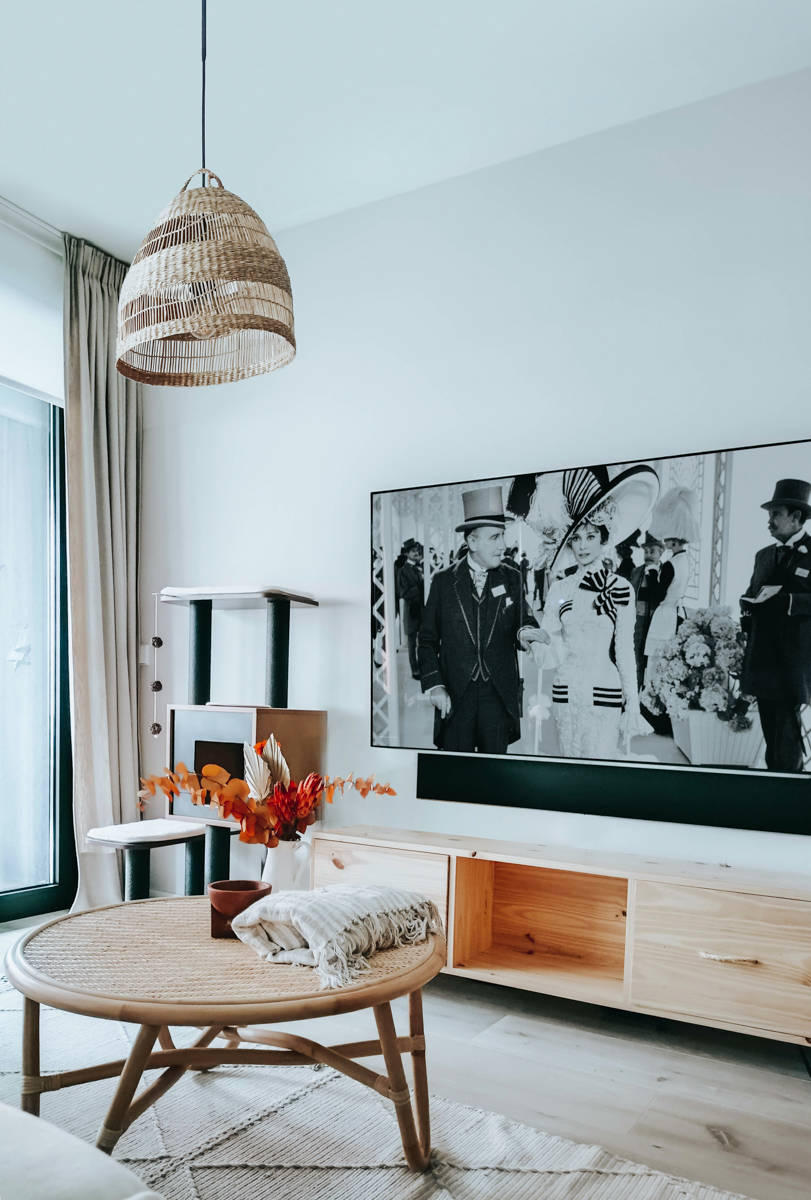 Zona de estar con mueble de televisor de madera, cortinas beige y la´mapra de fibras por Ana Villaman~an