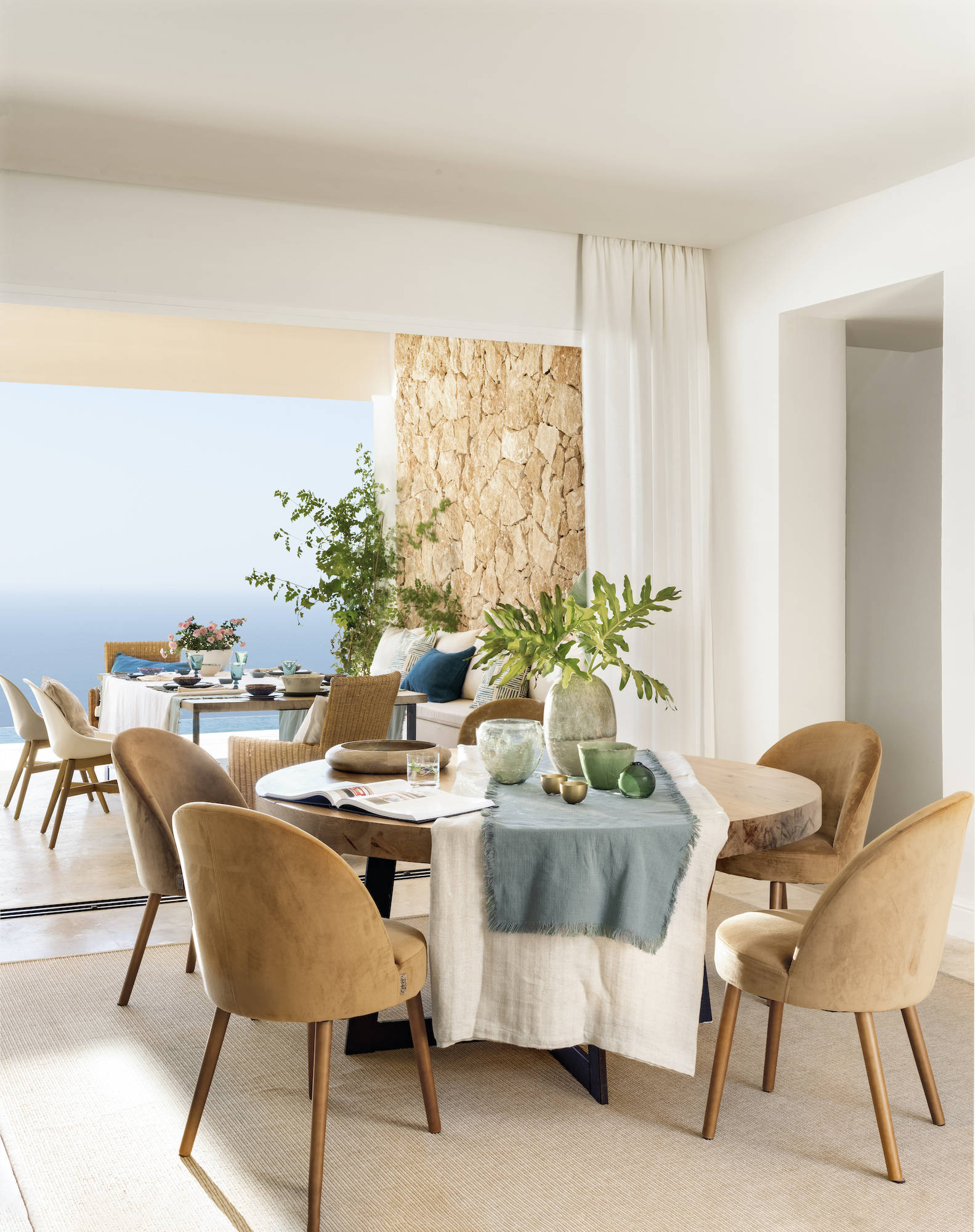 Comedor moderno con mesa redonda de madera y sillas tapizadas en mostaza. 