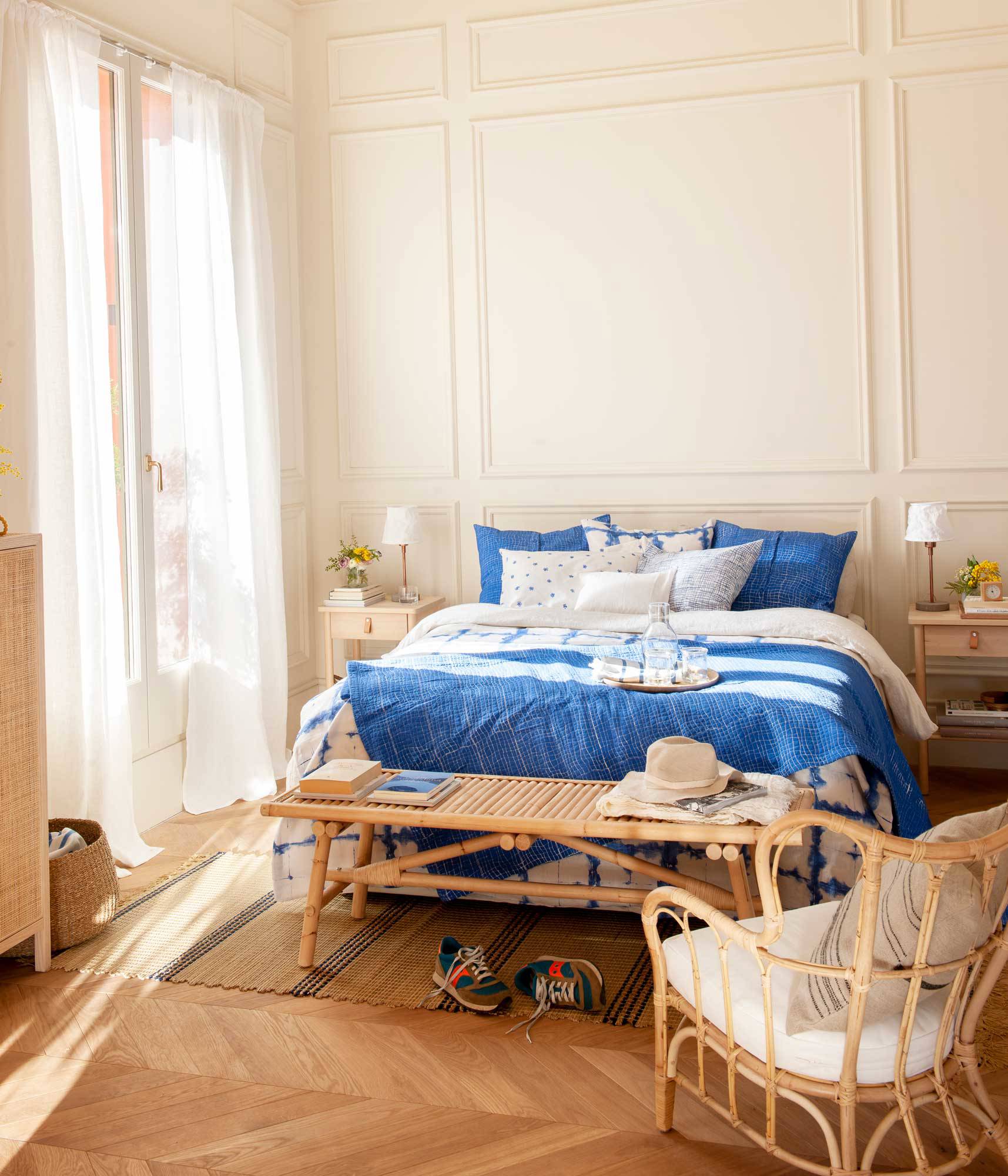 Dormitorio con molduras en la pared, muebles de madera y fibra, y ropa de cama azul.