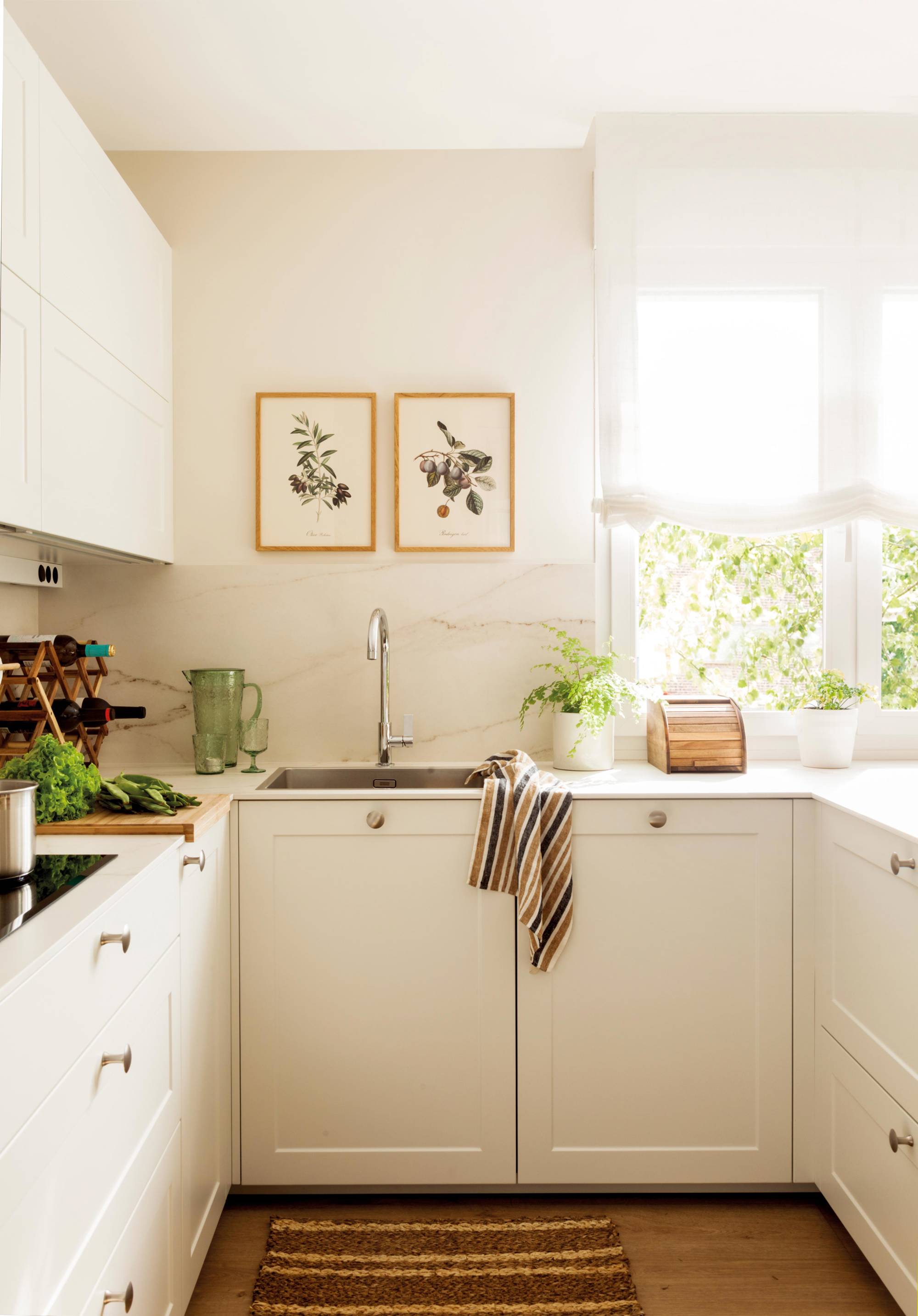 Small white kitchen with knobs and pictures. 