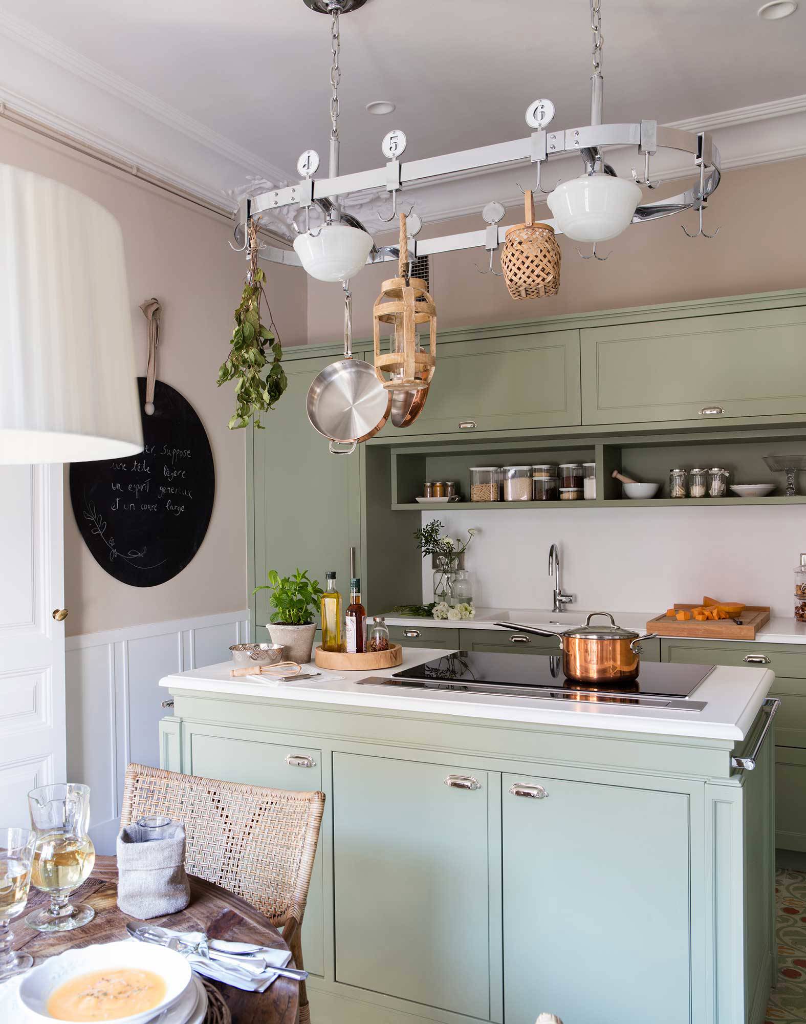 Small green kitchen with island and walls with moldings. 