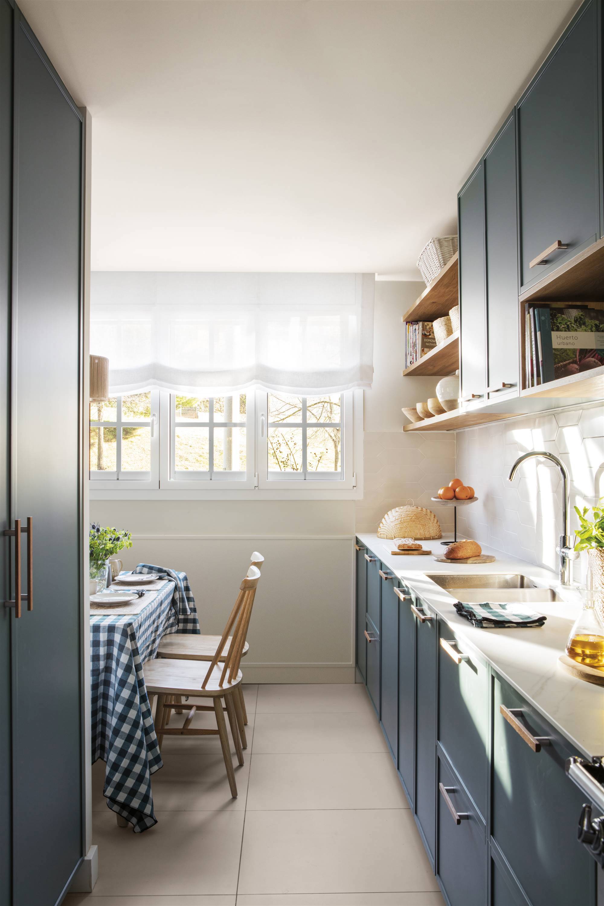 Small, modern blue kitchen with white worktop. 
